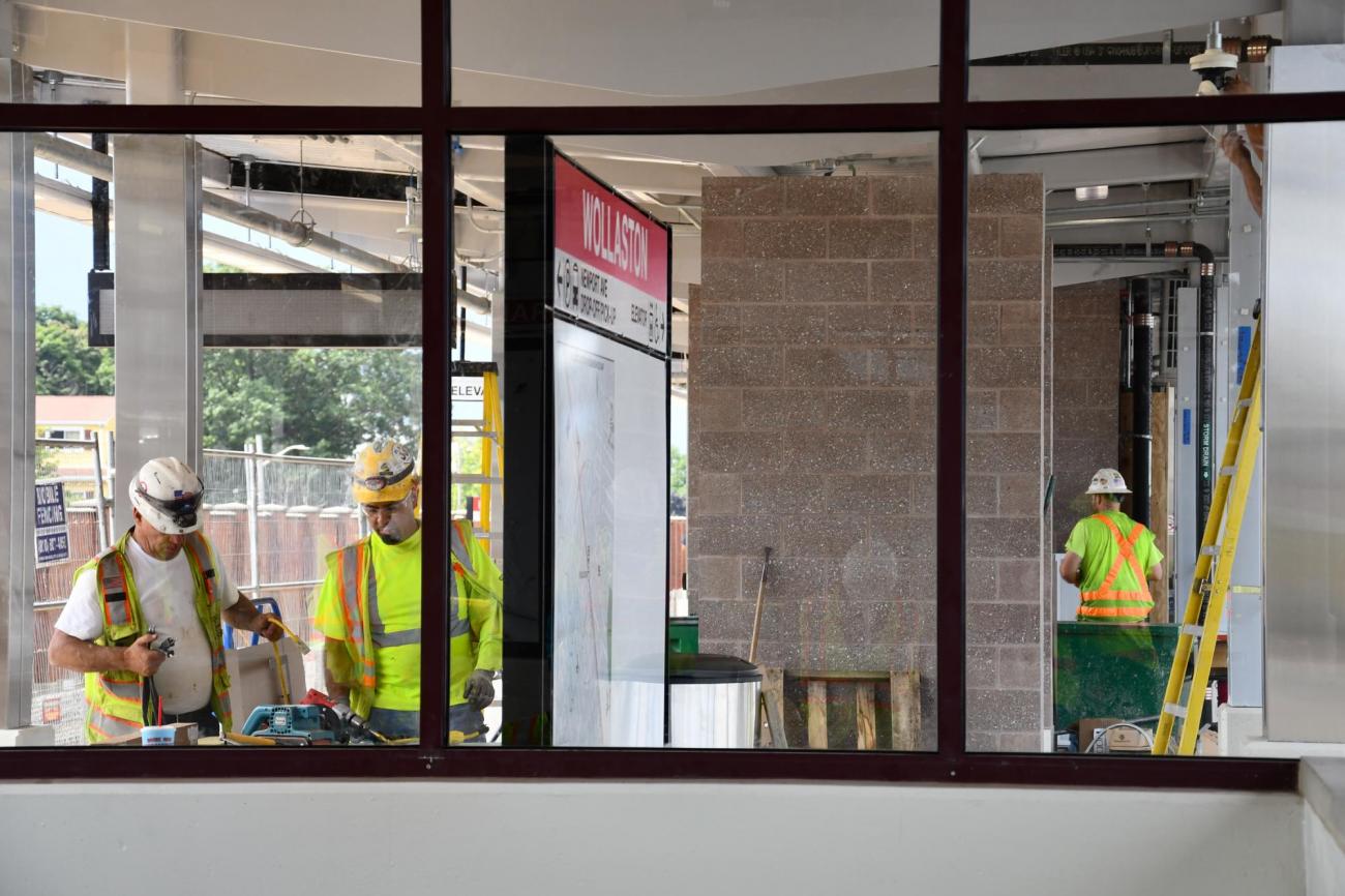 Viewed through a window, crews work at Wollaston Station during the final stages of renovation. (August 7, 2019)