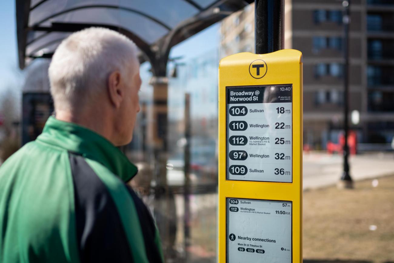 A rider reads the new E Ink sign at the Broadway bus stop in Everett