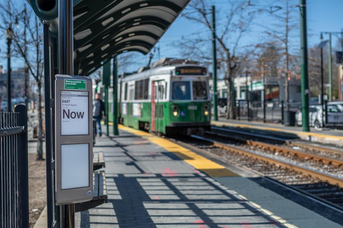 A Green Line C train approaches the Washington Square inbound stop, with an e-ink sign saying "Now."