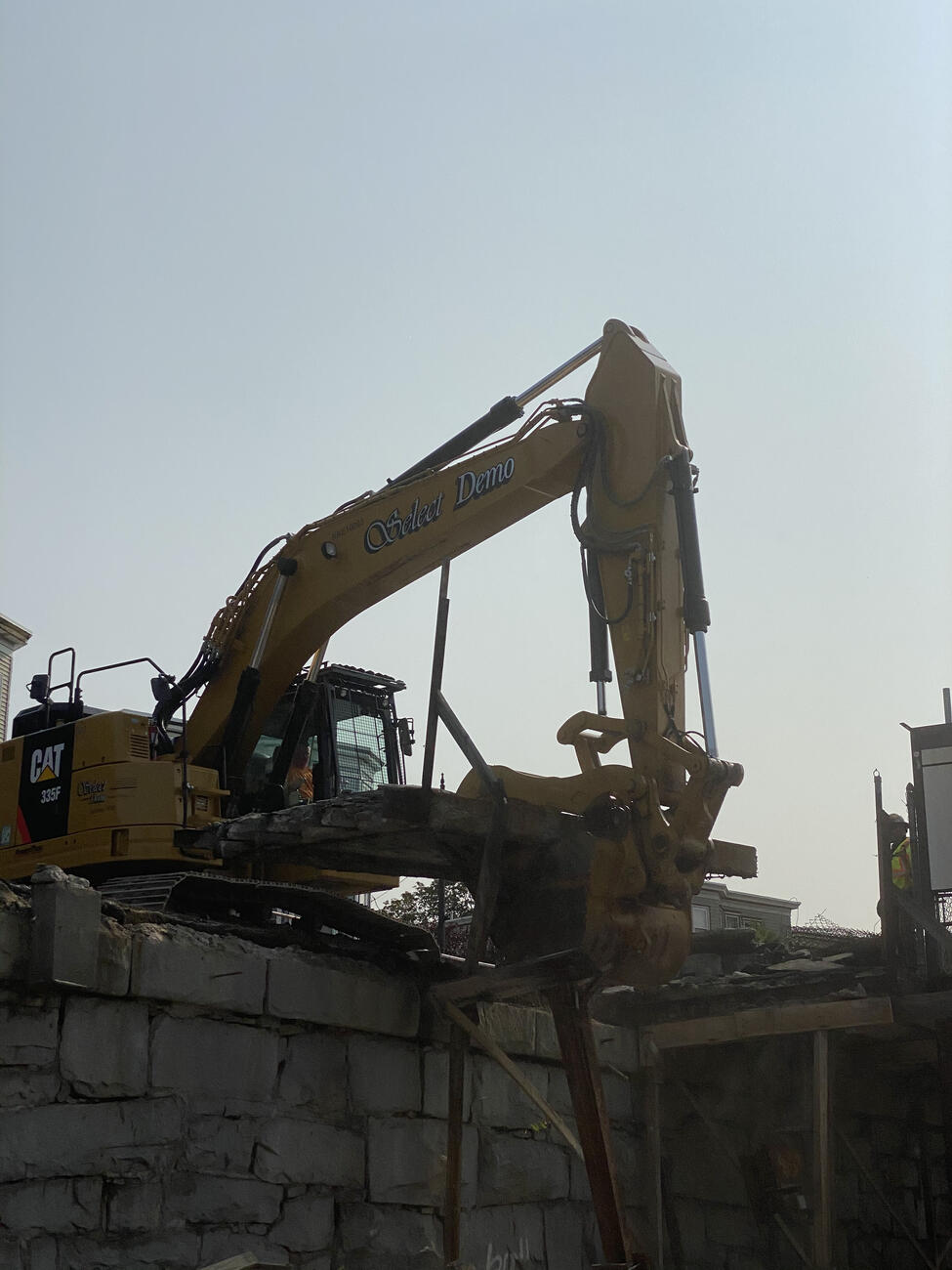 Large yellow excavator working to repair the Porter Square retaining wall.