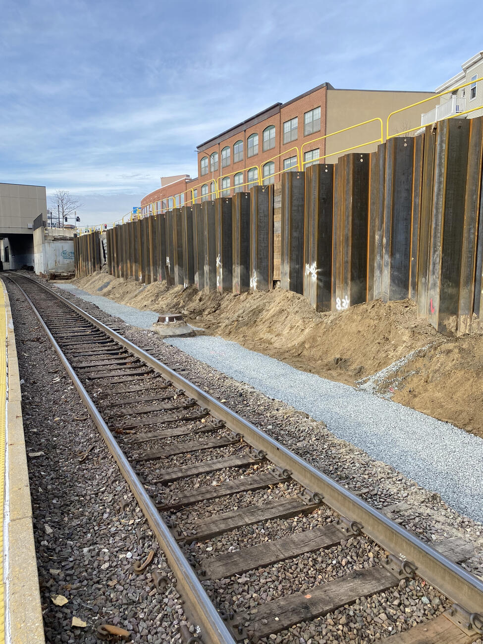 A picture of the construction work taken from the station platform. The tracks are in the foreground and large, tall metal sheets have been installed next to the wall to stabilize it.