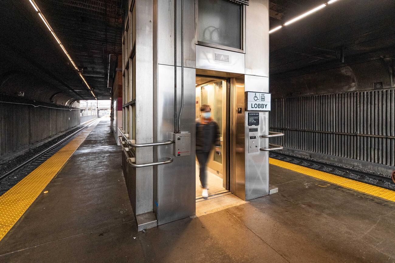 A passenger exits elevator 849 onto the platform between tracks 1 and 3 at Ruggles station. This elevator takes riders from the lobby to the Commuter Rail tracks, which are shown to the left and right of the elevator.