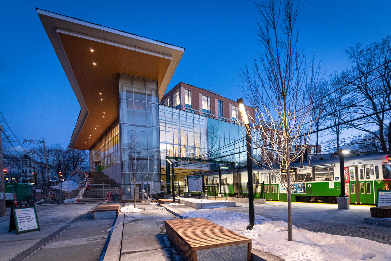An exterior shot of the updated Brookline Hills station (a mostly glass building) at dawn with snow on the ground