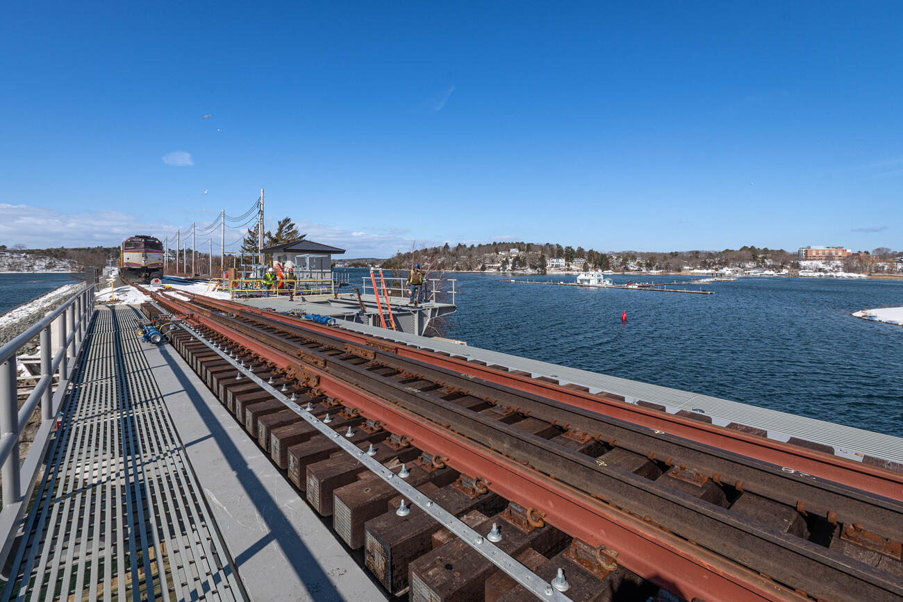 a commuter rail train is shown stopped just short of the gloucester drawbridge