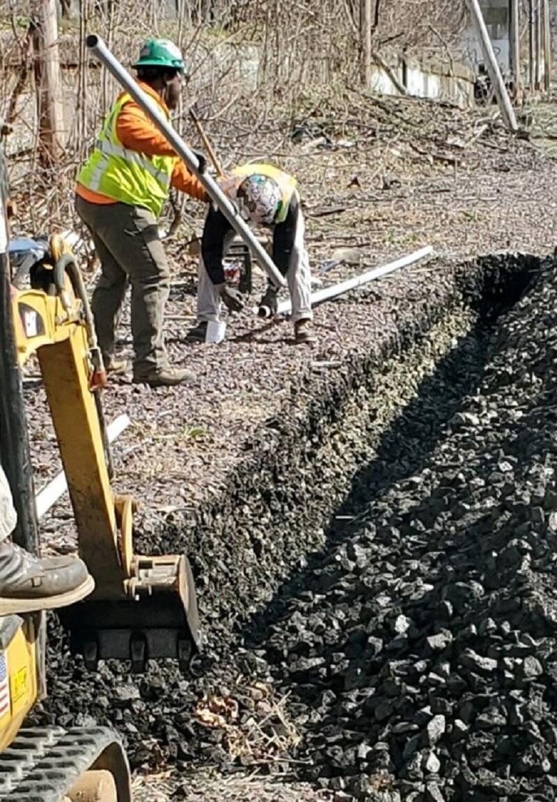 Image of crews trenching along tracks on Newburyport Line to install ATC signal conduit