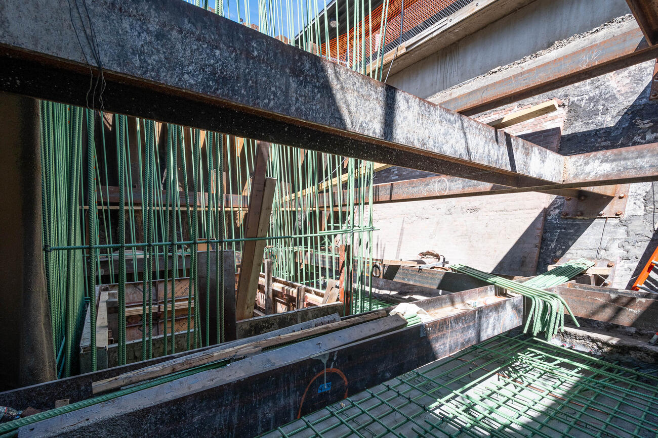 Steel reinforcement bars hang and lay around a metal foundation. The steel bars will reinforce the concrete beneath an elevator on the new platform.