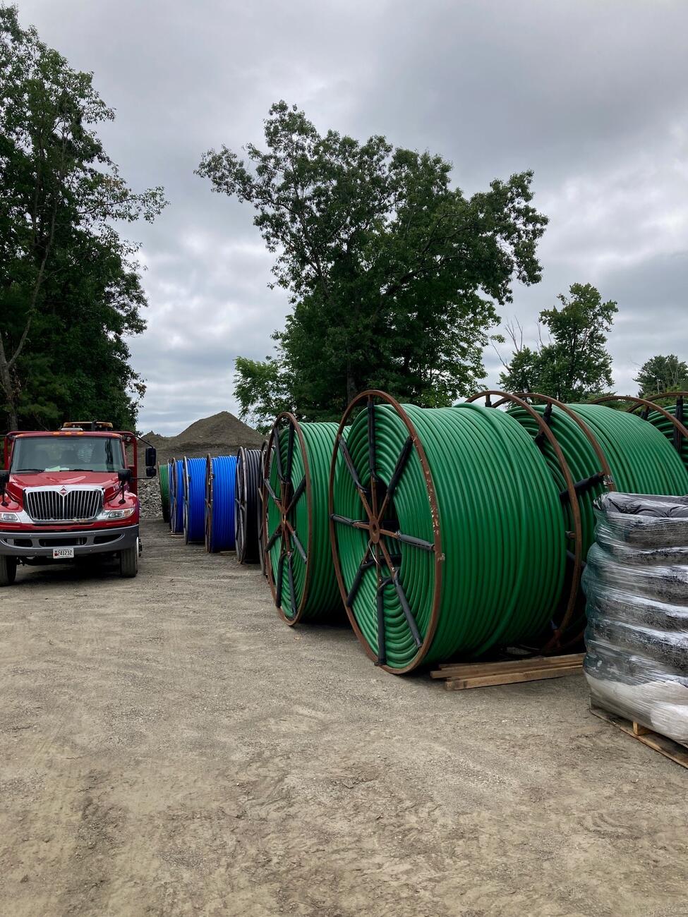 Large reels of green and blue innerduct sit outside next to a red truck.