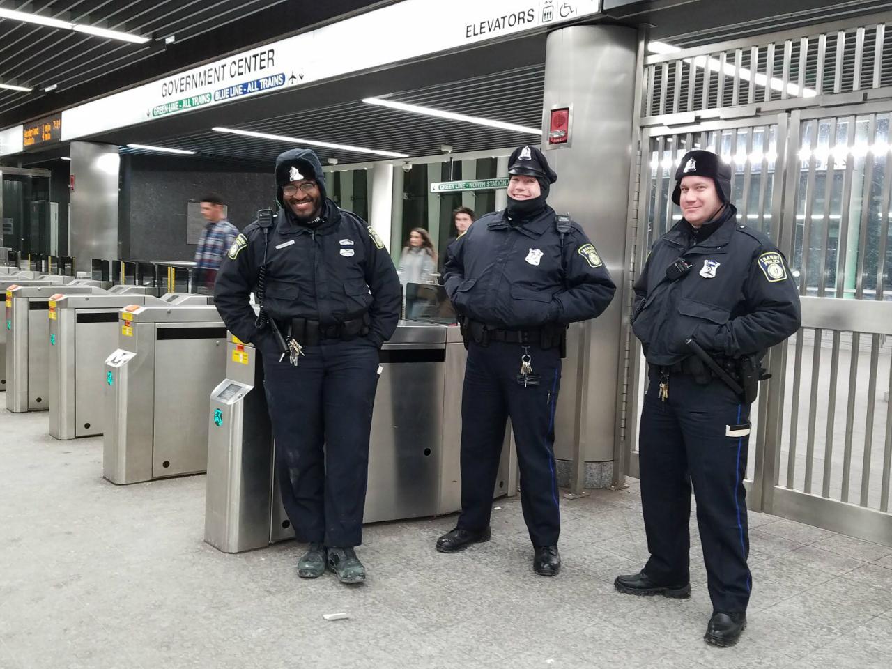 Three Transit Police officers, bundled up in winter gear, stand near the fare gates at Government Center Station on New Year's Eve.