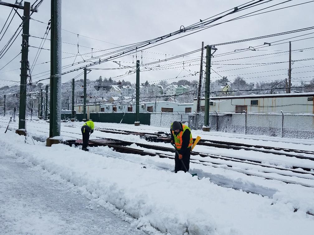 Crewmen shovel snow along the tracks