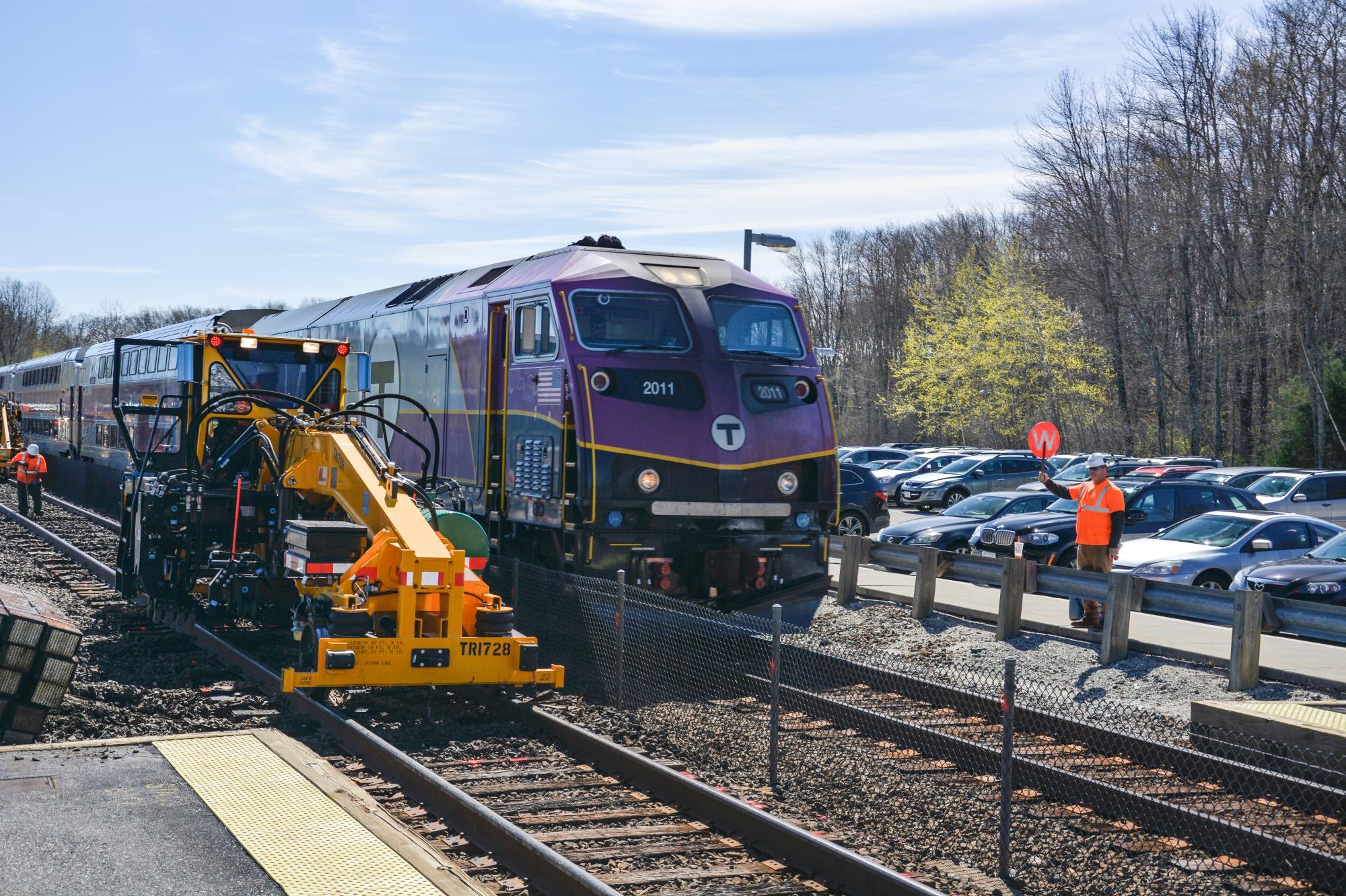 A Commuter Rail train with machinery by its side, the track ties being replaced