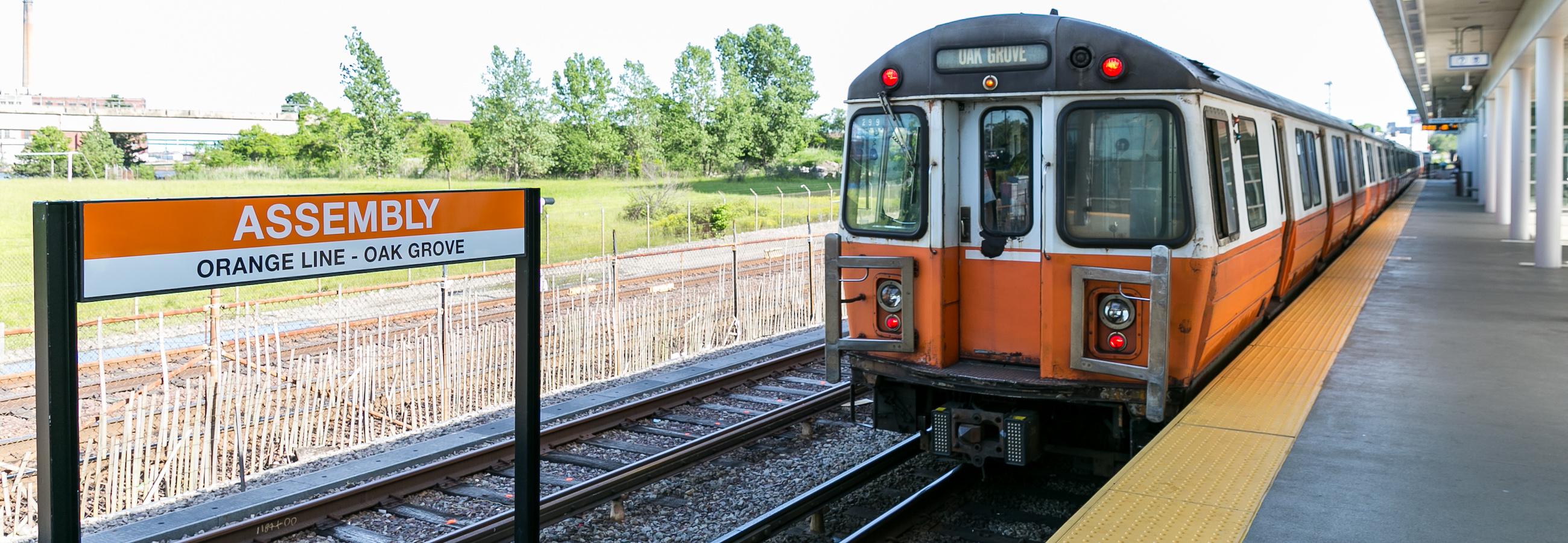 Orange Line Train Pulling into Assembly Station with Sign