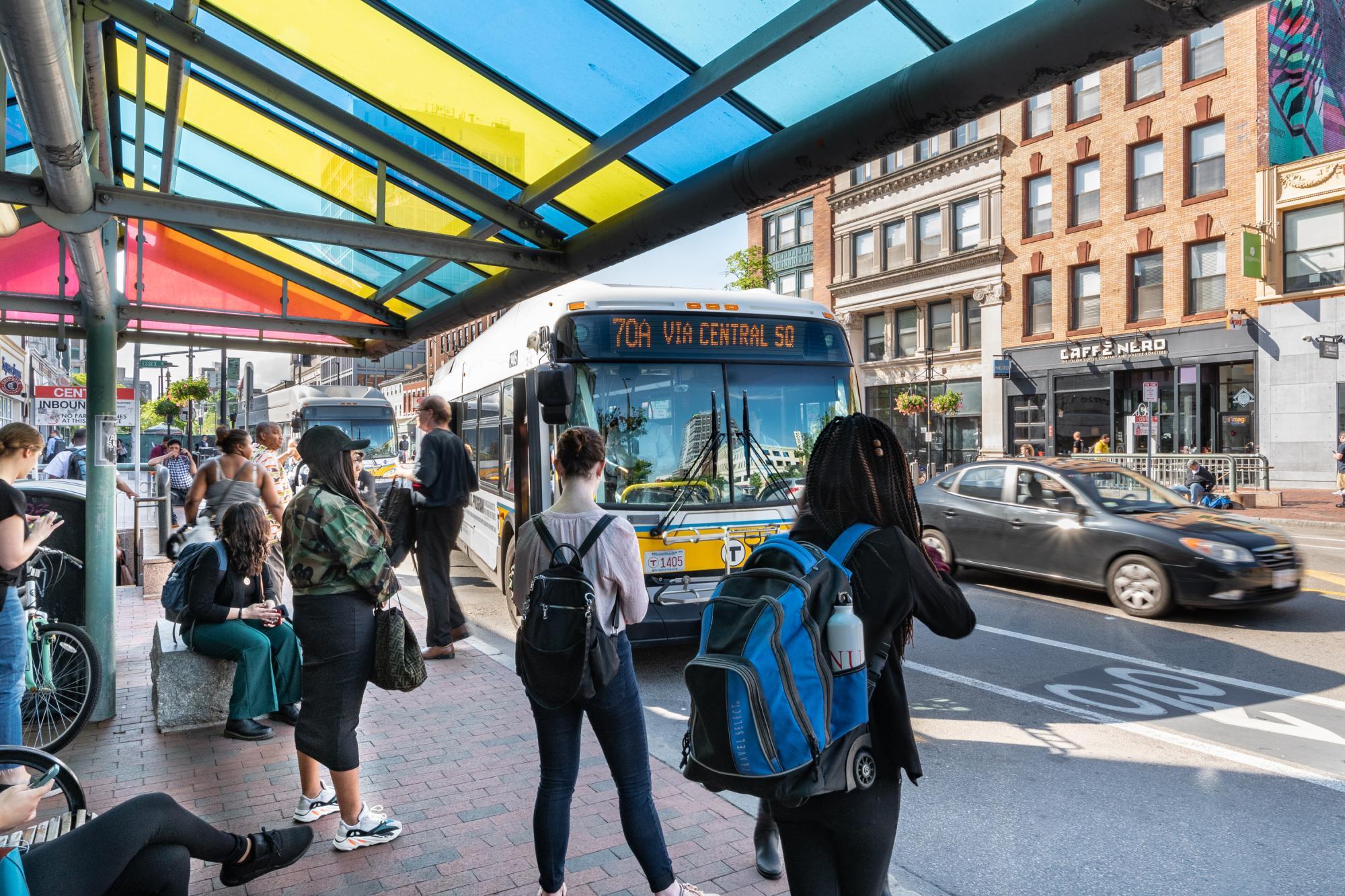 Riders wait on Massachusetts Ave in Central Square, Cambridge, while a 70A bus pulls up to the stop.