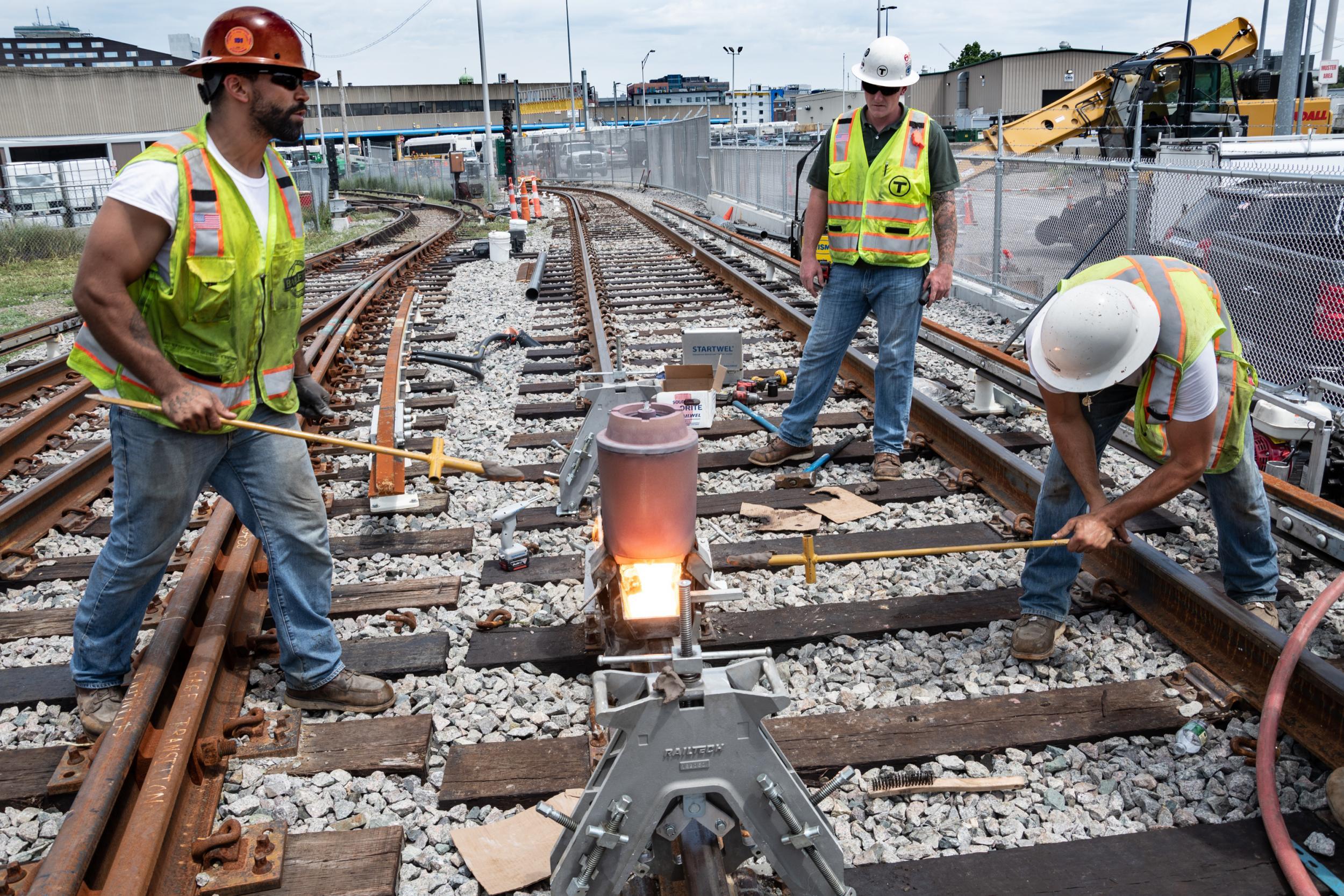 A crew along the Red Line test track in Cabot Yard uses exothermic welding to fuse separate pieces of rail together.