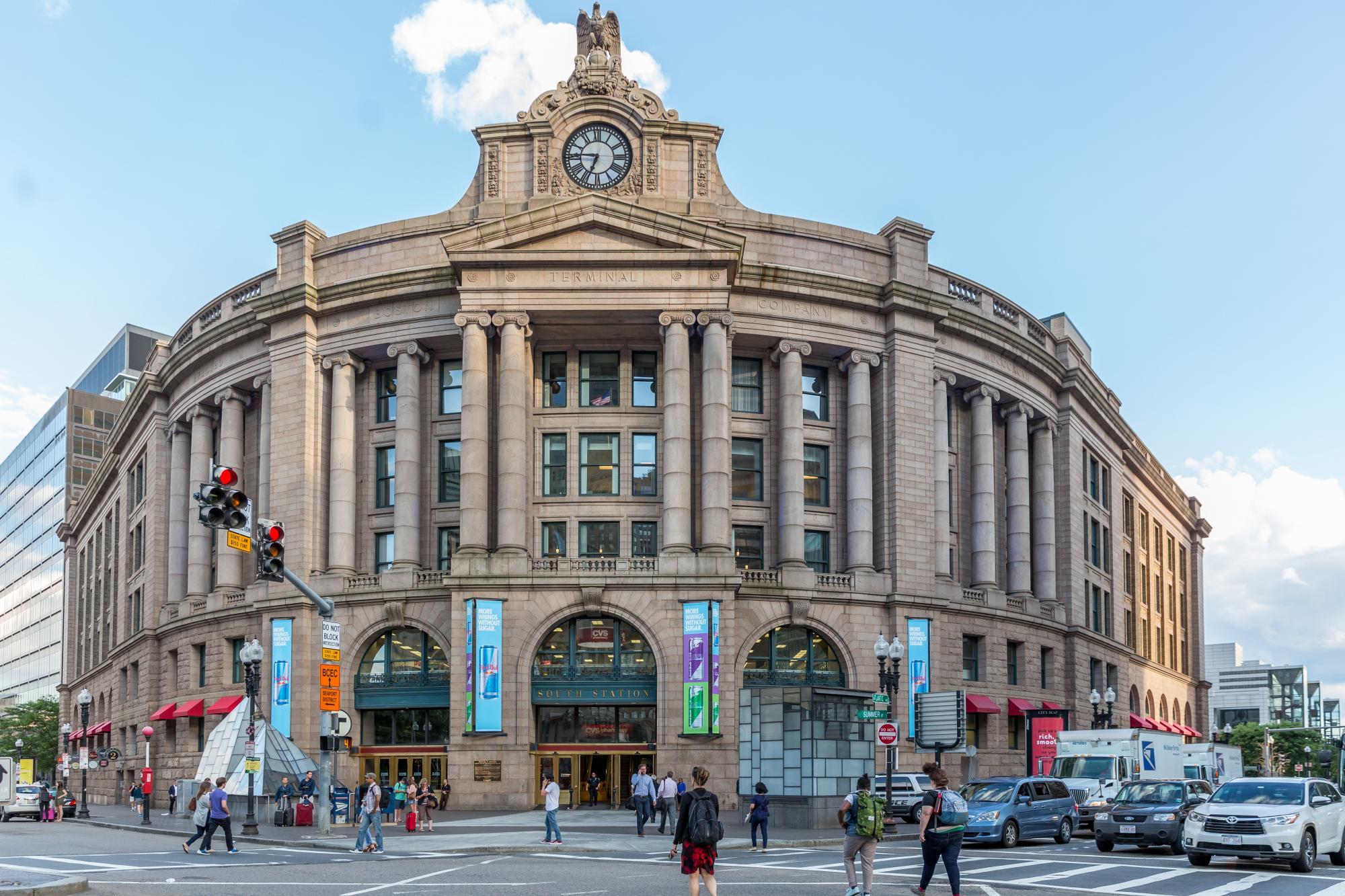 The facade of South Station, with pedestrians and traffic also pictured.