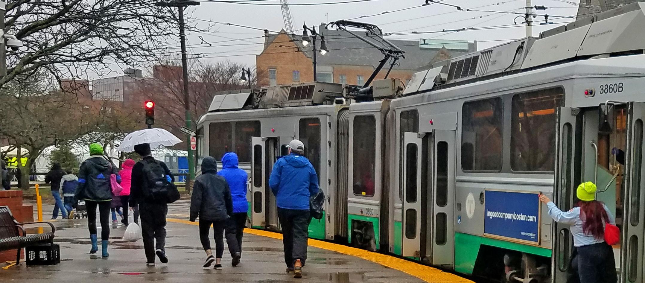 Riders near the Green Line during rainy weather at Boston Marathon 2018