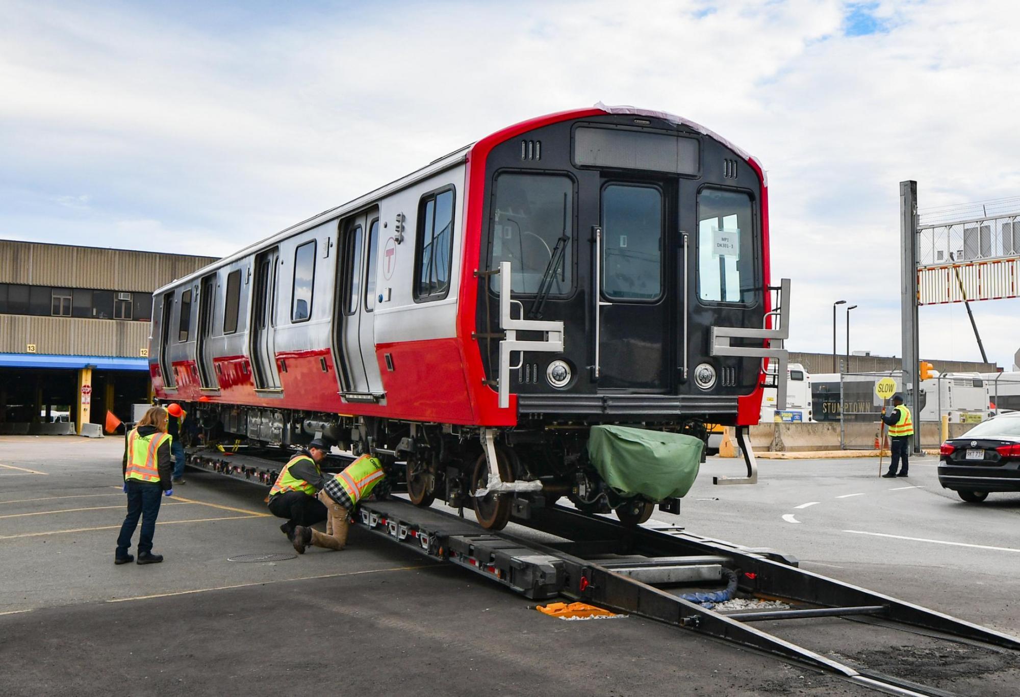 A new Red Line car delievered to Cabot Yard. MBTA workers help get it off the trailer.