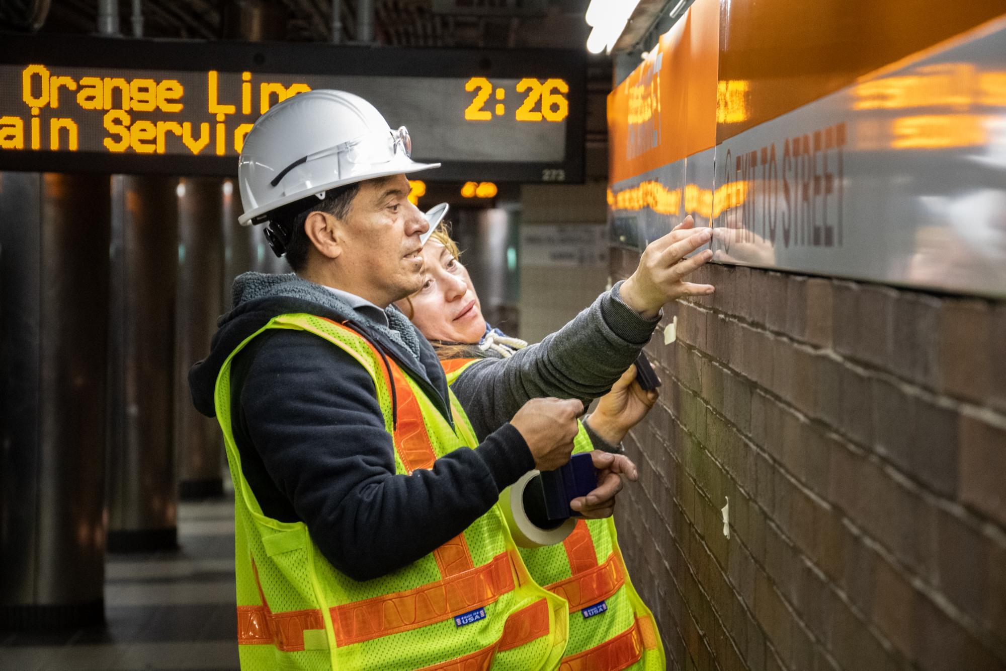 Crew members install new wayfinding signs on the Haymarket platform during the November 1 – 3, 2019 weekend shutdown 