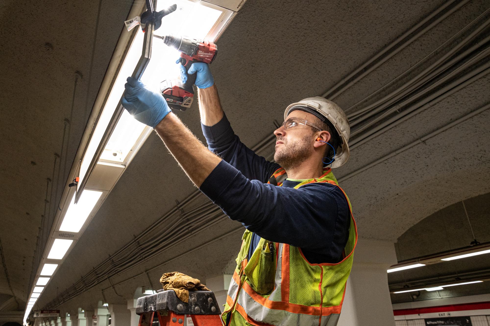 A crew member replaces a light fixture at Downtown Crossing as part of the Red Line beautifucation and track work during the November 15 – 17 weekend shutdown