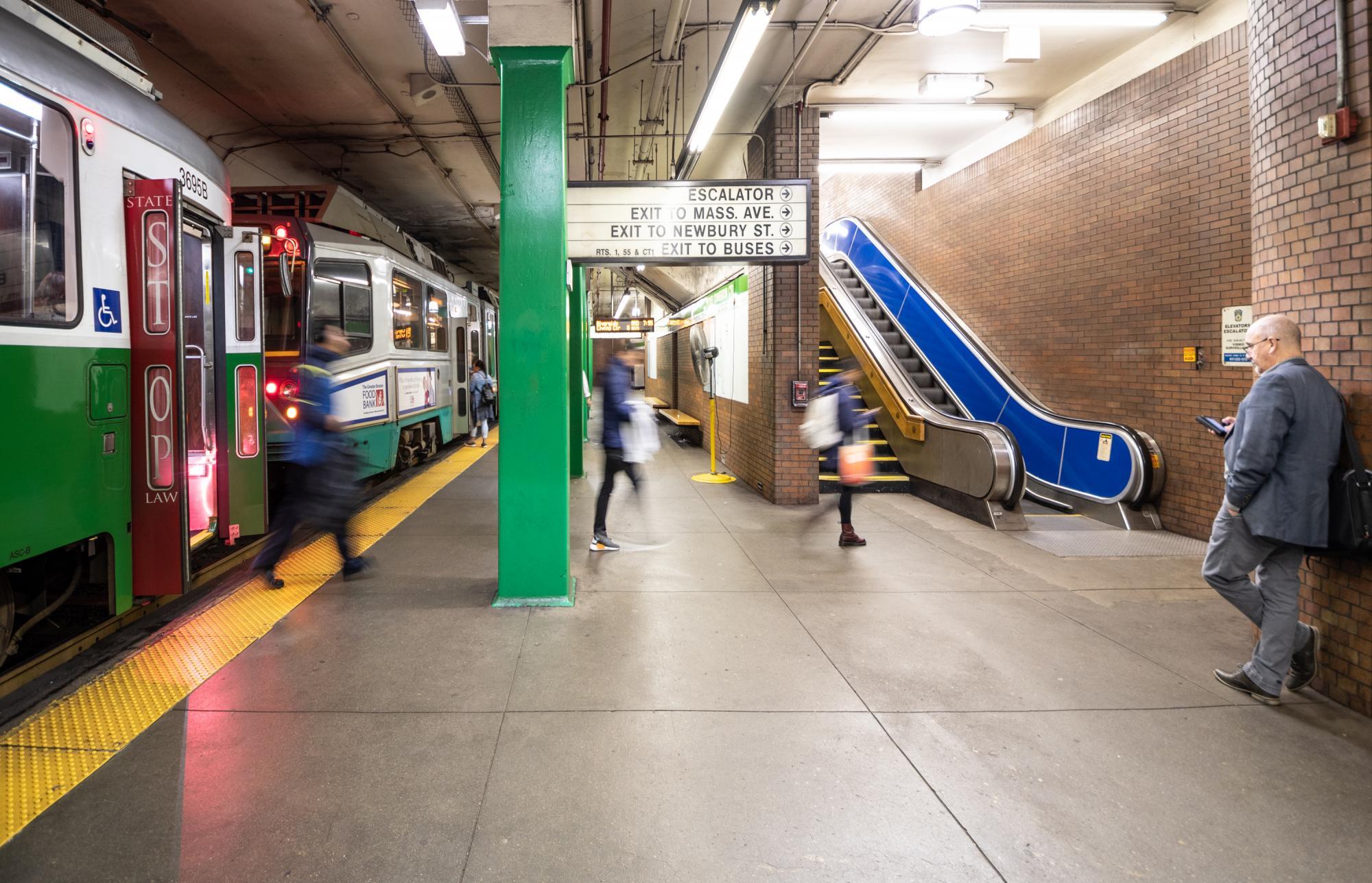 Riders disembark a Green Line train at Hynes Station