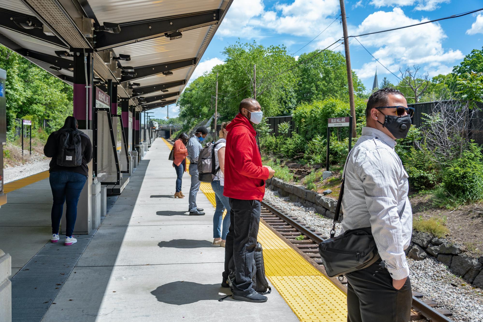 Customers at the Blue Hill Ave Commuter Rail platform, wearing face coverings