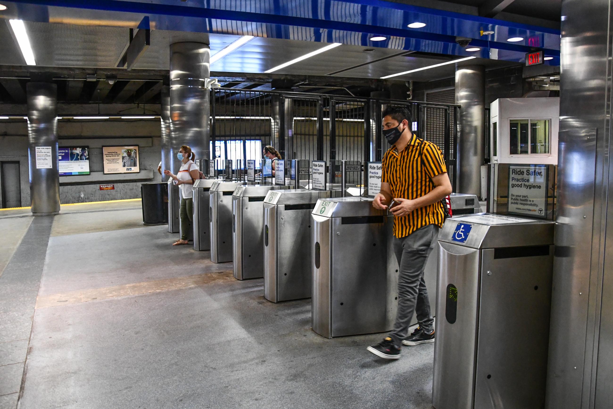 A Blue Line rider wearing a face mask passes through fare gates at Maverick Station