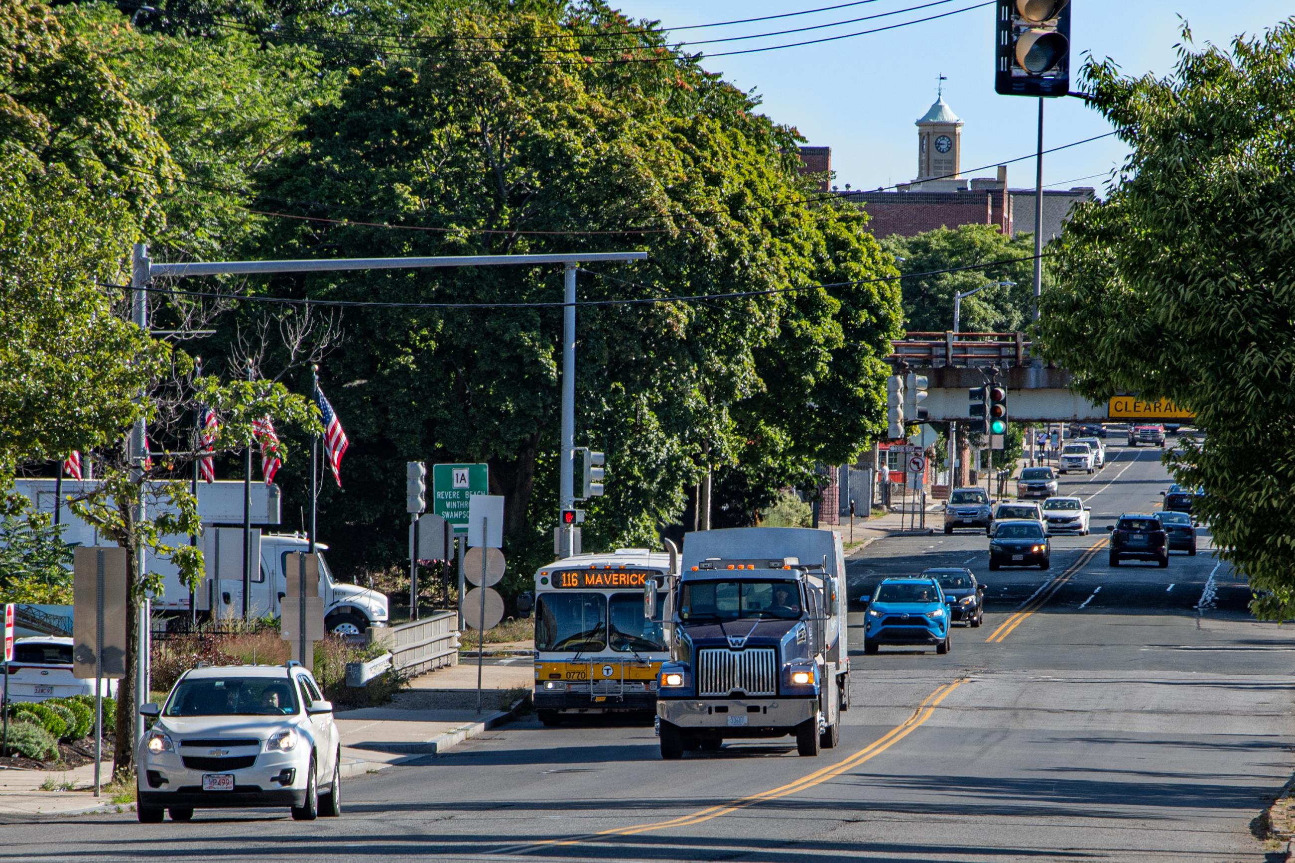 View of Broadway Ave in Chelsea on a cloudless summer day. The 116 bus is in light traffic.