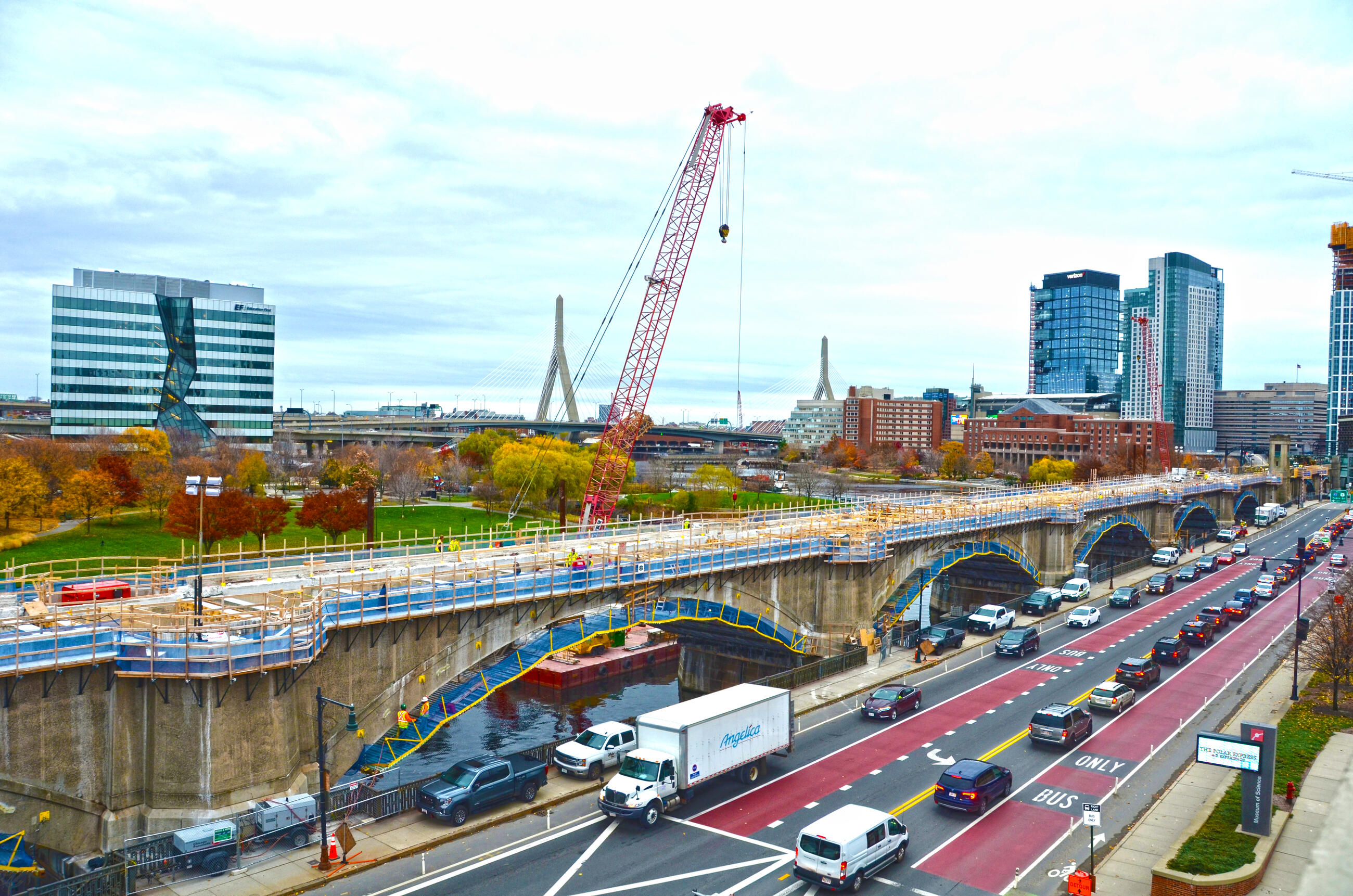 Crews working on the Lechmere Viaduct Rehabilitation with the city and fall foliage in the background 