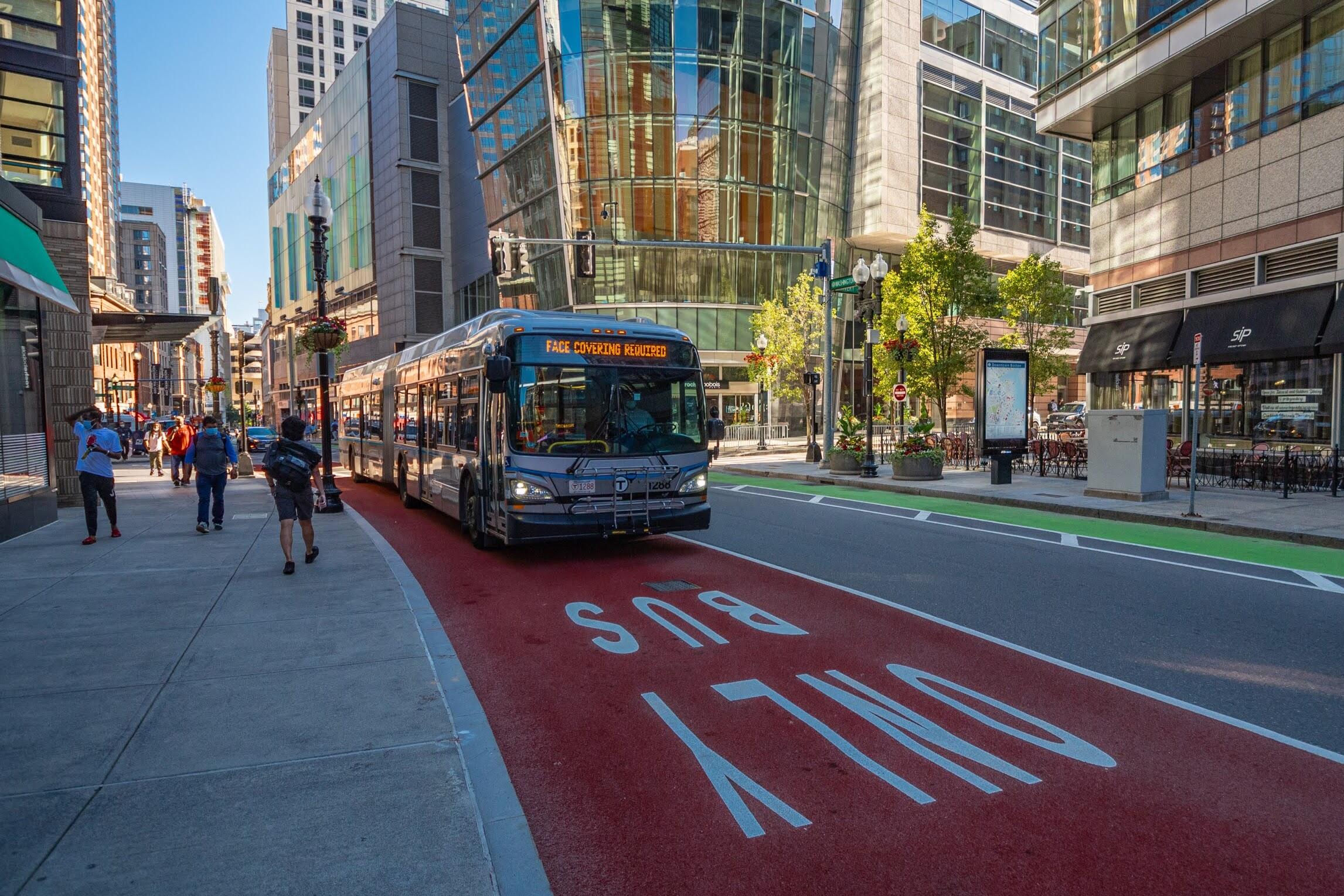 Silver Line bus in a bus lane along Washington St in Downton Boston, with a headsdign that reads "Face Masks Required"