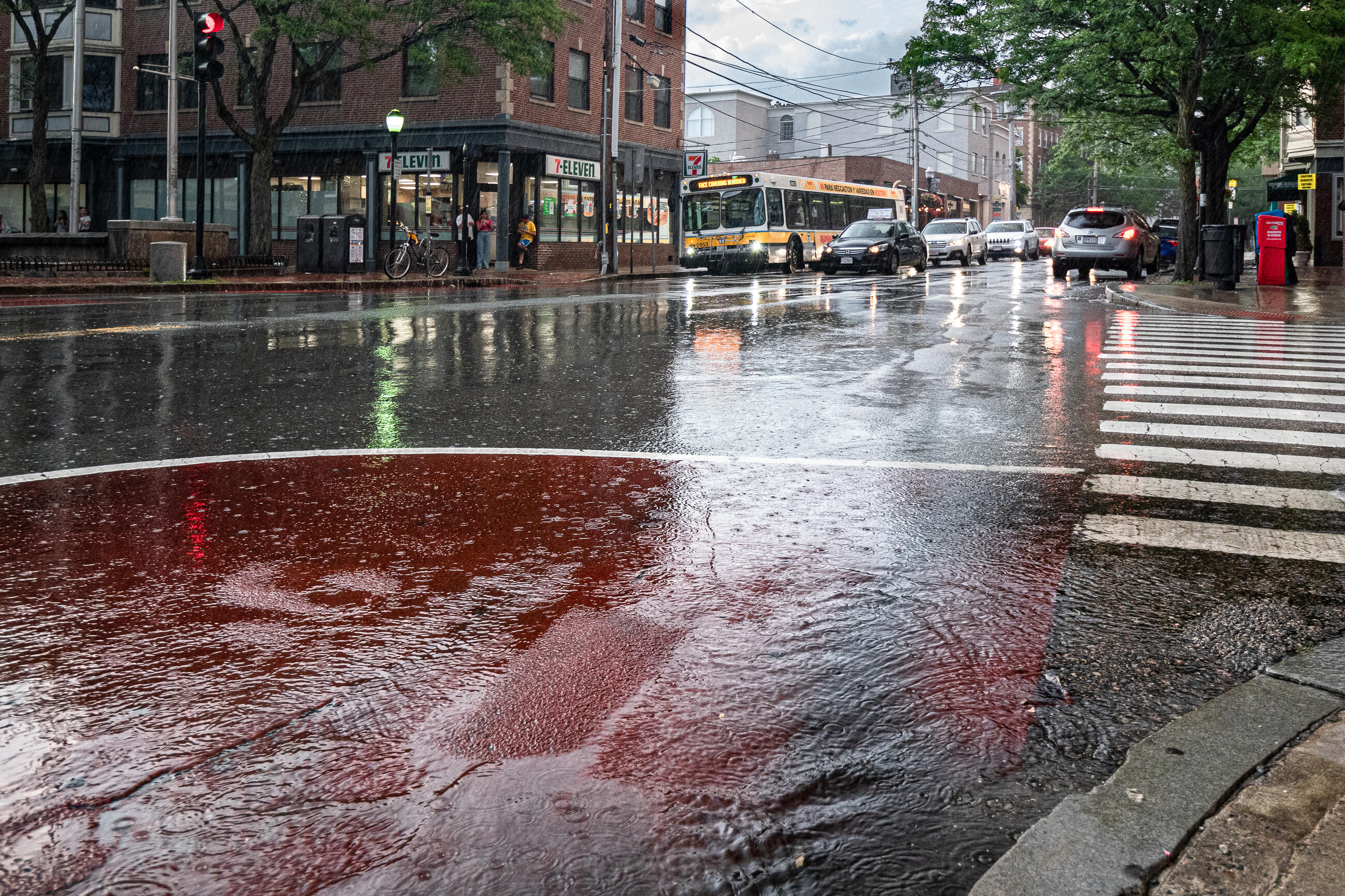 large puddle in Davis Square with rain and MBTA bus in background