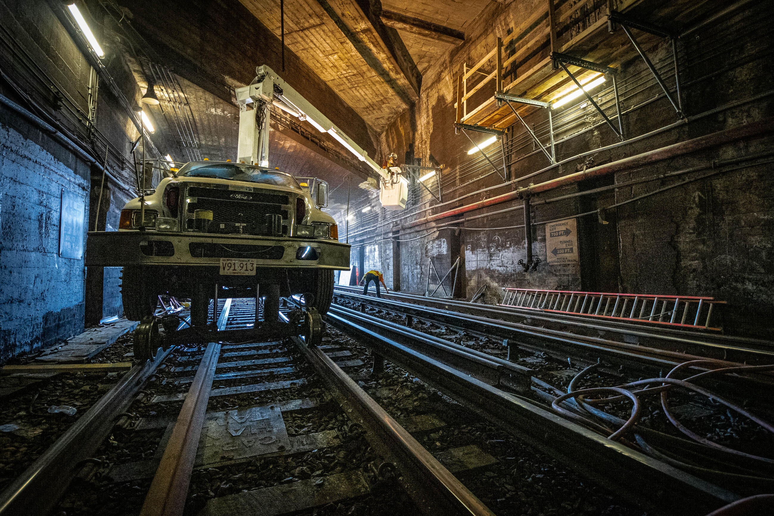truck on tracks with tunnel work in the background takes place under the Dorchester Avenue Bridge on the Red Line