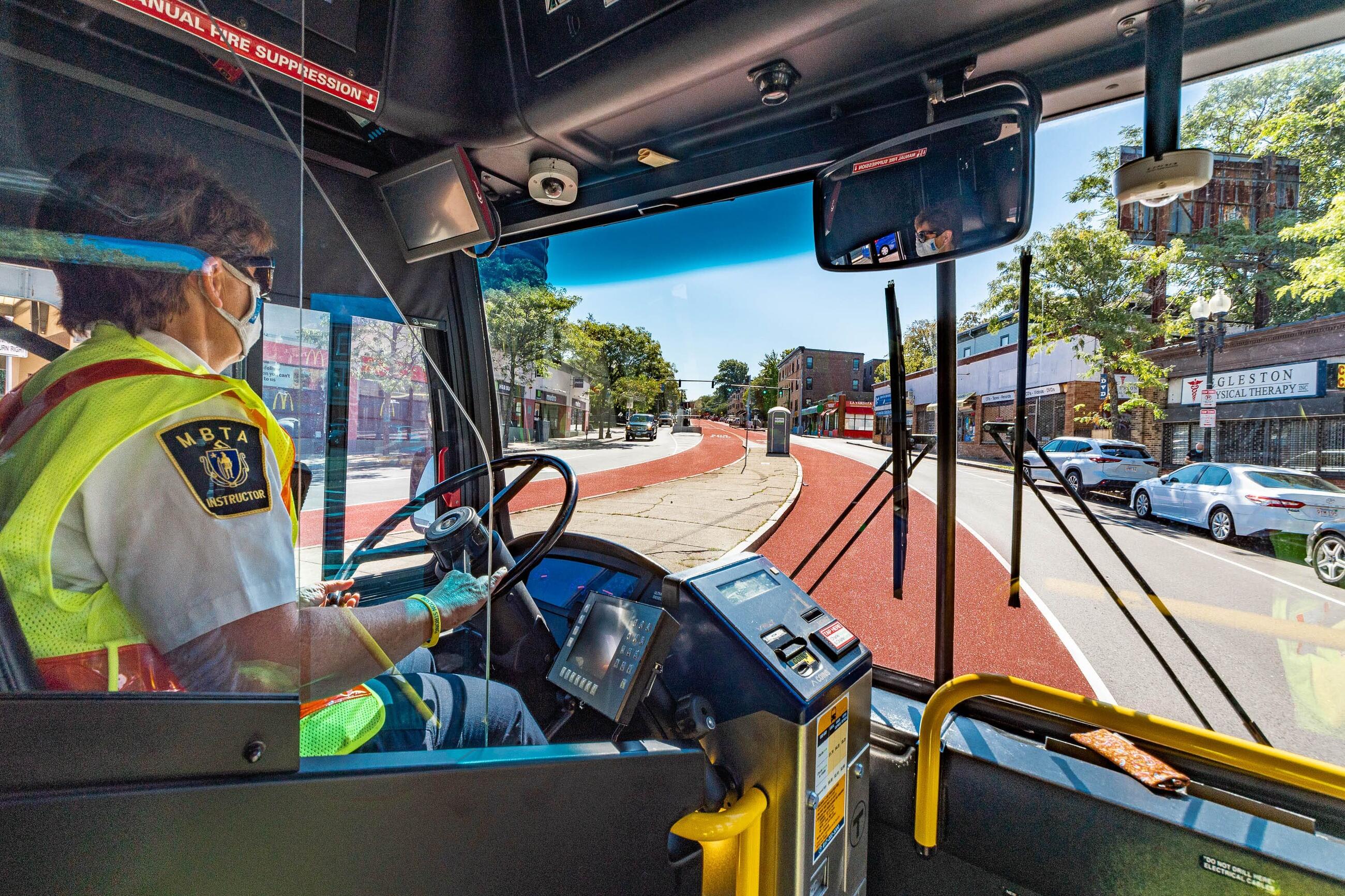 Photo taken from inside a bus of a masked driver with an 