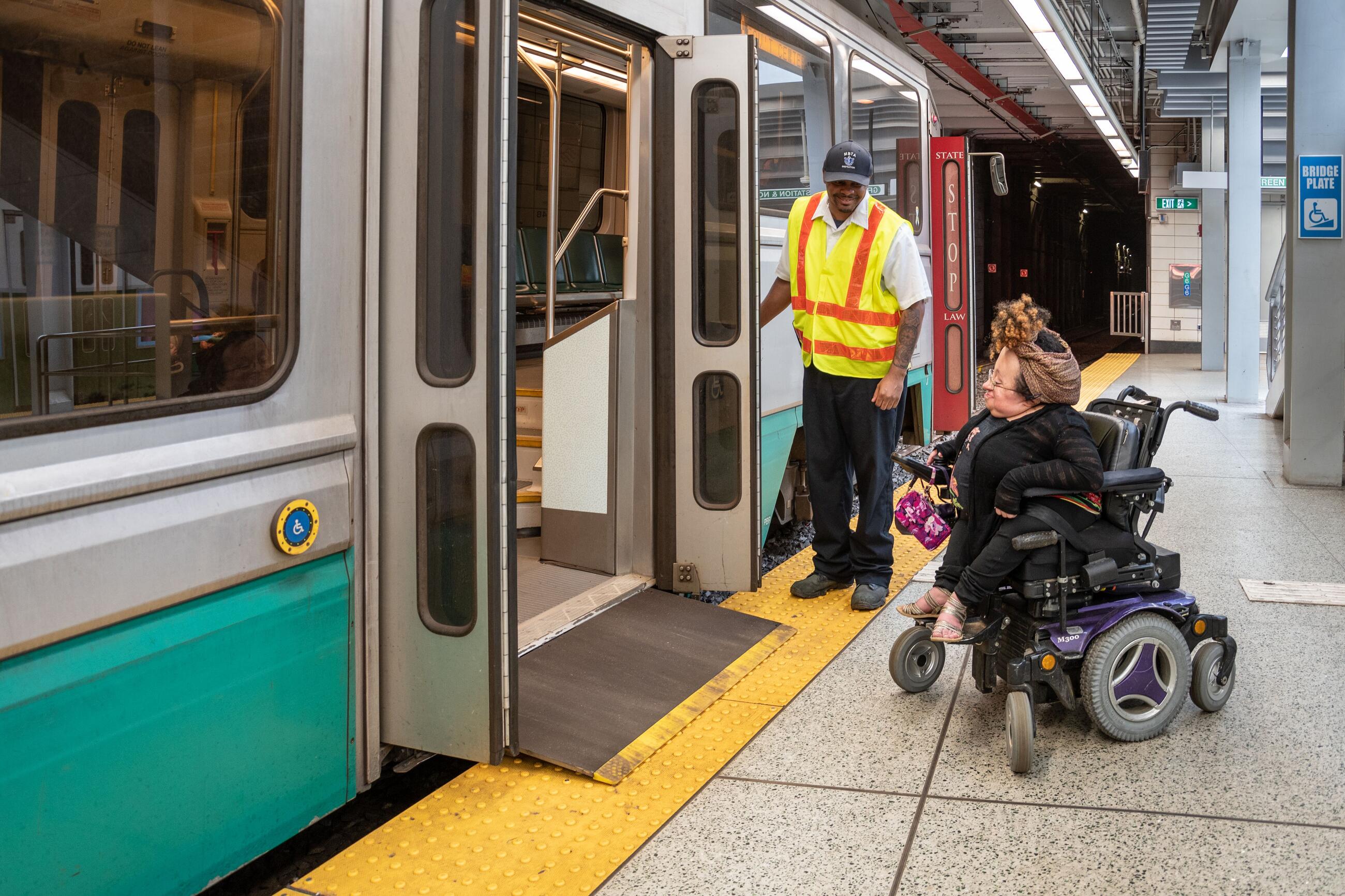 On the Green Line, an operator stands by the doors, as the bridge plate allows a rider in a wheeled mobility device to board