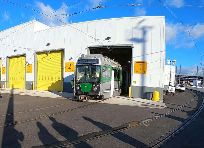 The Green Line Extension test trolley leaves a vehicle maintenance facility bay marked 