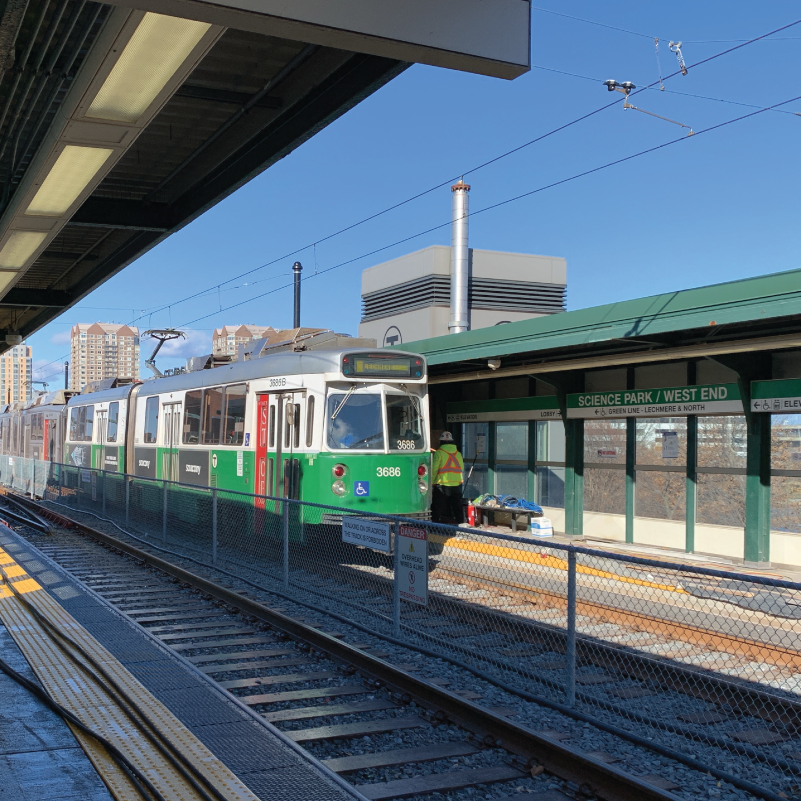 A green line trolley in front of Science Park/West End station on a sunny day