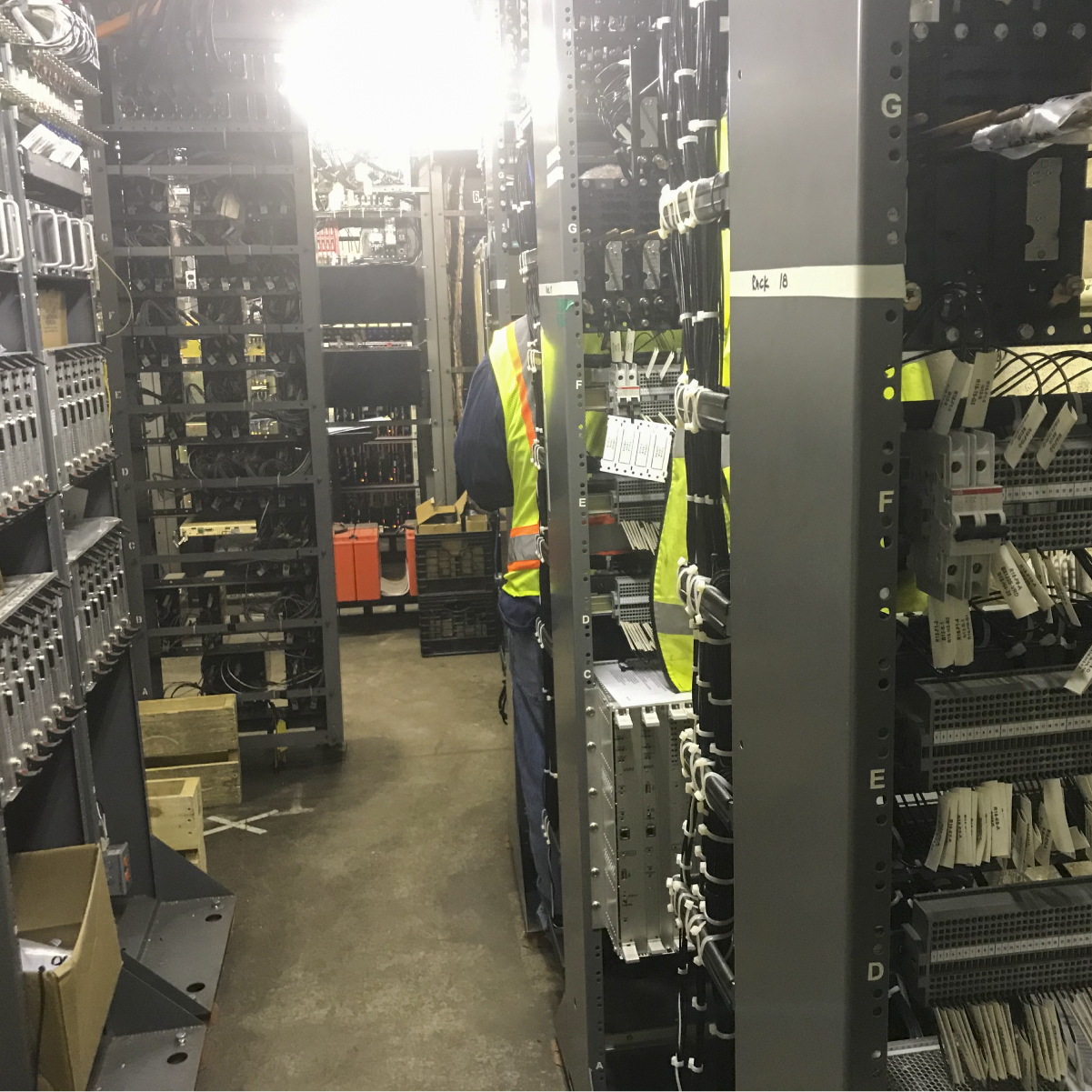 an employee in a high visibility vest stands between signal racks