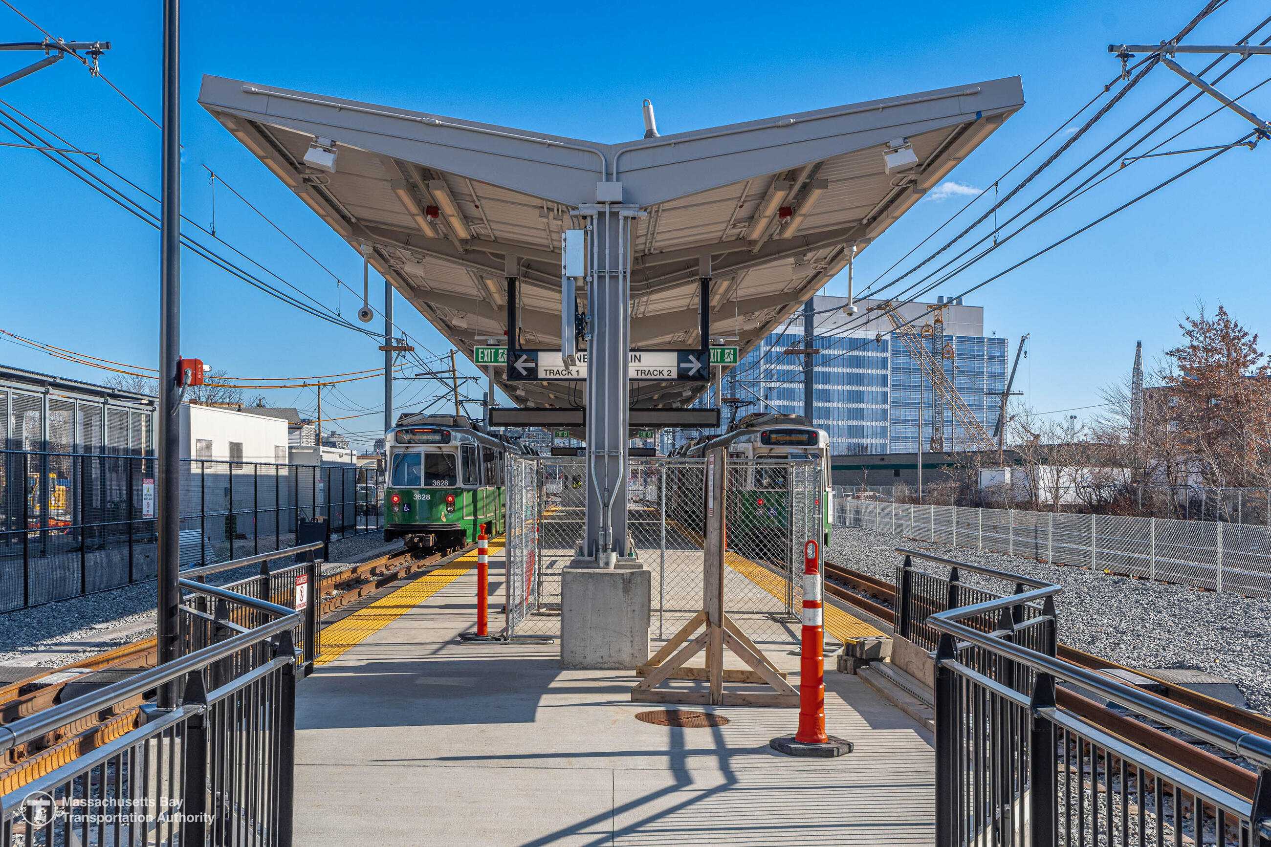 Two test trollies arrive and depart the new Union Square station. The station was under construction at the time the trollies were tested, so traffic cones and a temporary chain link fence sit on the platform between the two trains.