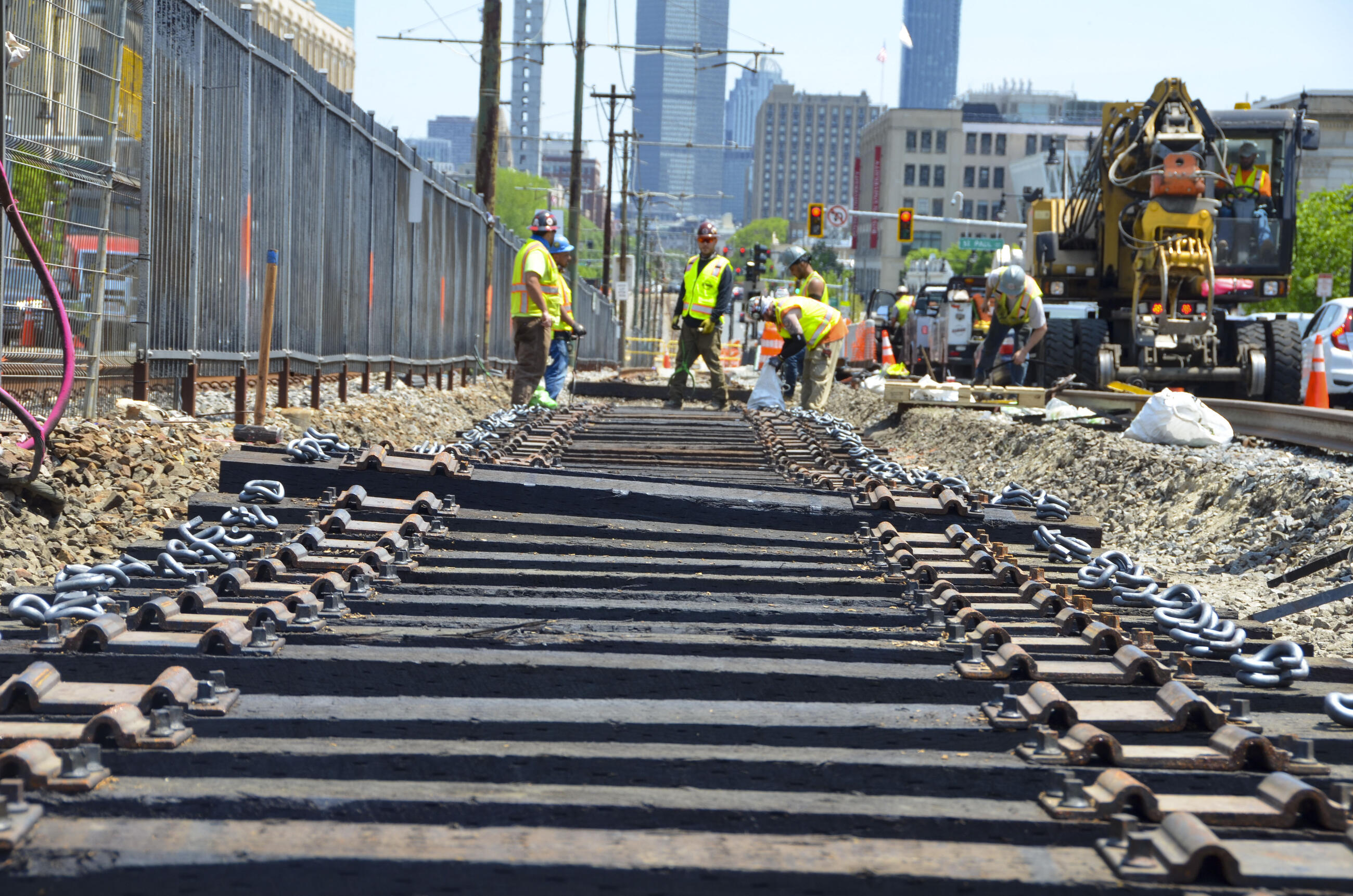six crew members in high vis and hard hats working on track on the b branch on a sunny day. many lines of track are in the foreground