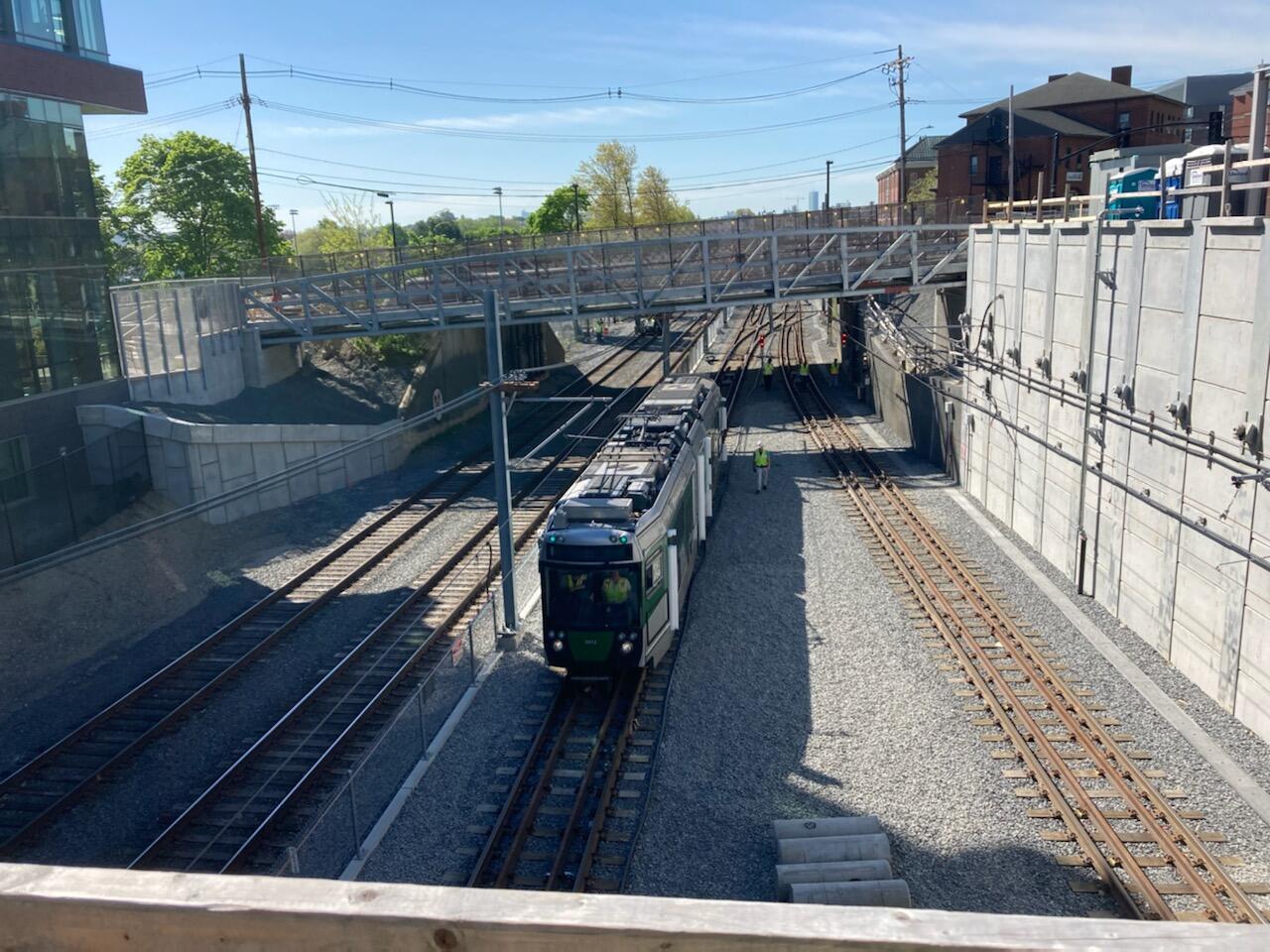 A green line test train passes under the pedestrian bridge at Tufts University 