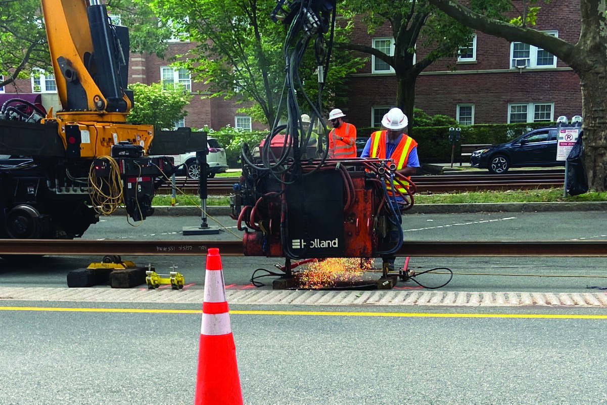 a crew member welding rail in the pavement with heavy machinery 