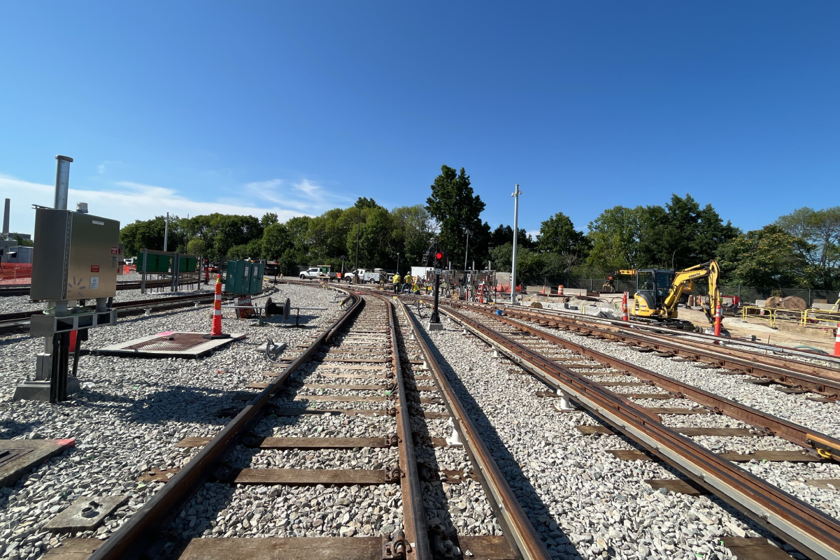 five sets of tracks on a sunny day, with a construction vehicle parked on the far right near some traffic cones