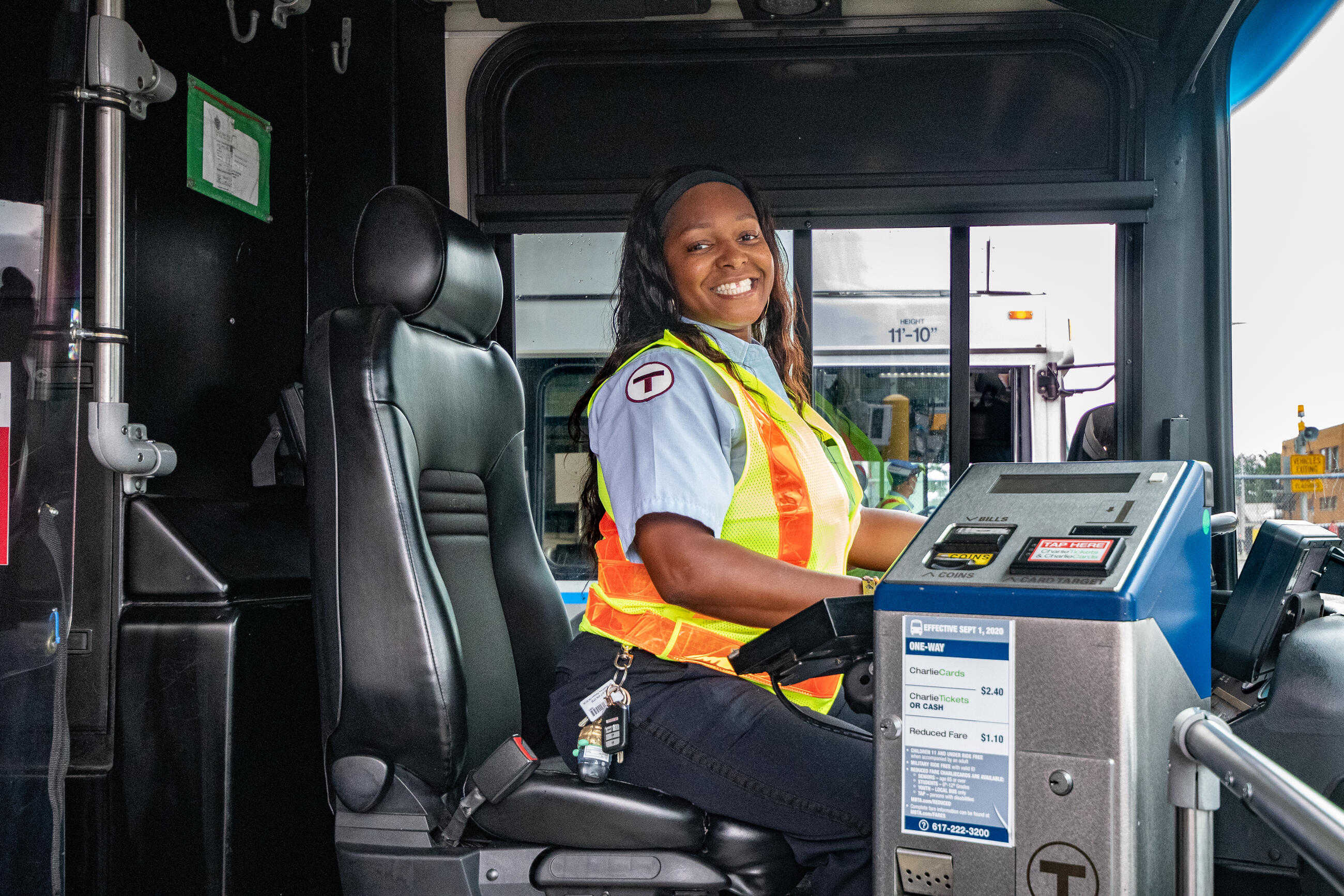 A bus operator is seated at the front of an MBTA bus