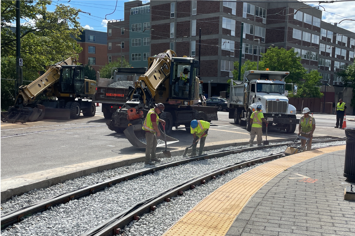 Workers placing ballast on tracks at the Heath St loop