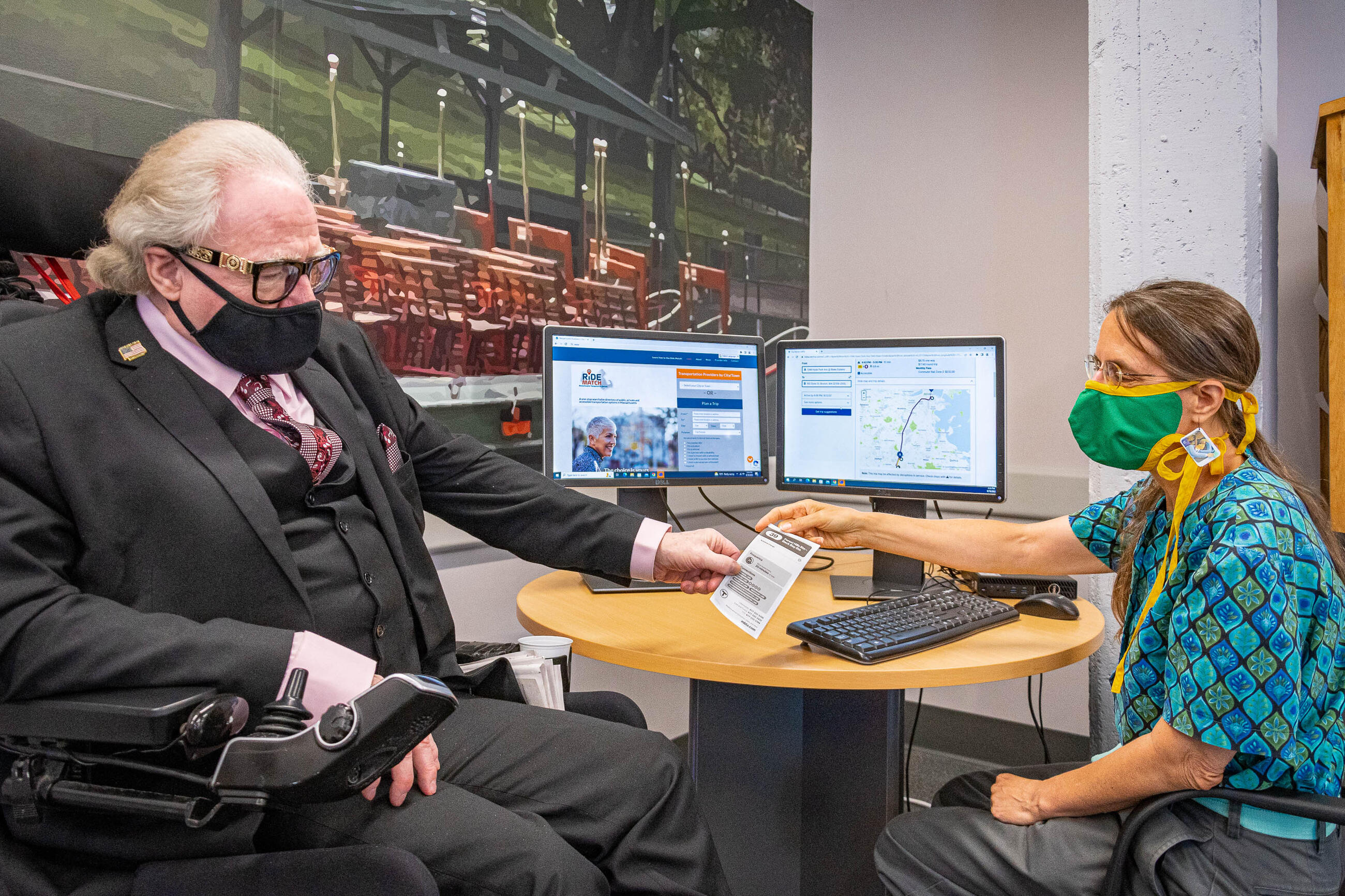 Rider being helped at the mobility center in front of a table with two computers 