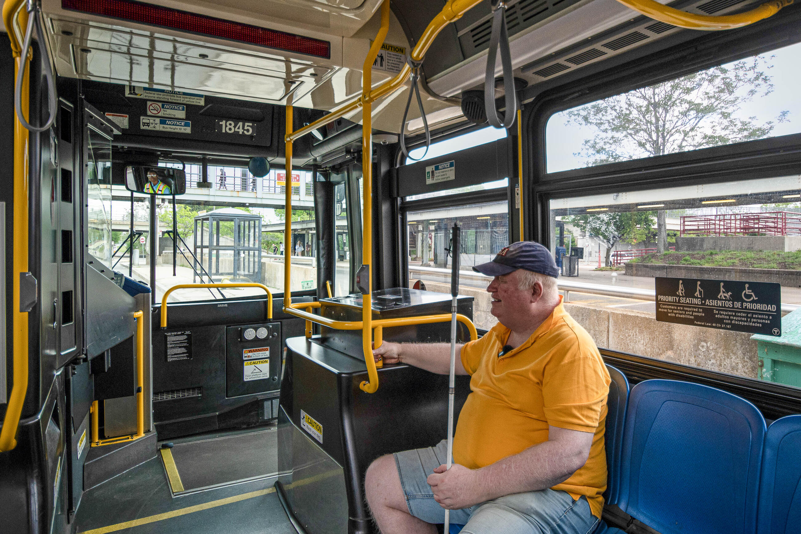 Rider sitting in priority seating area at the front of a bus 