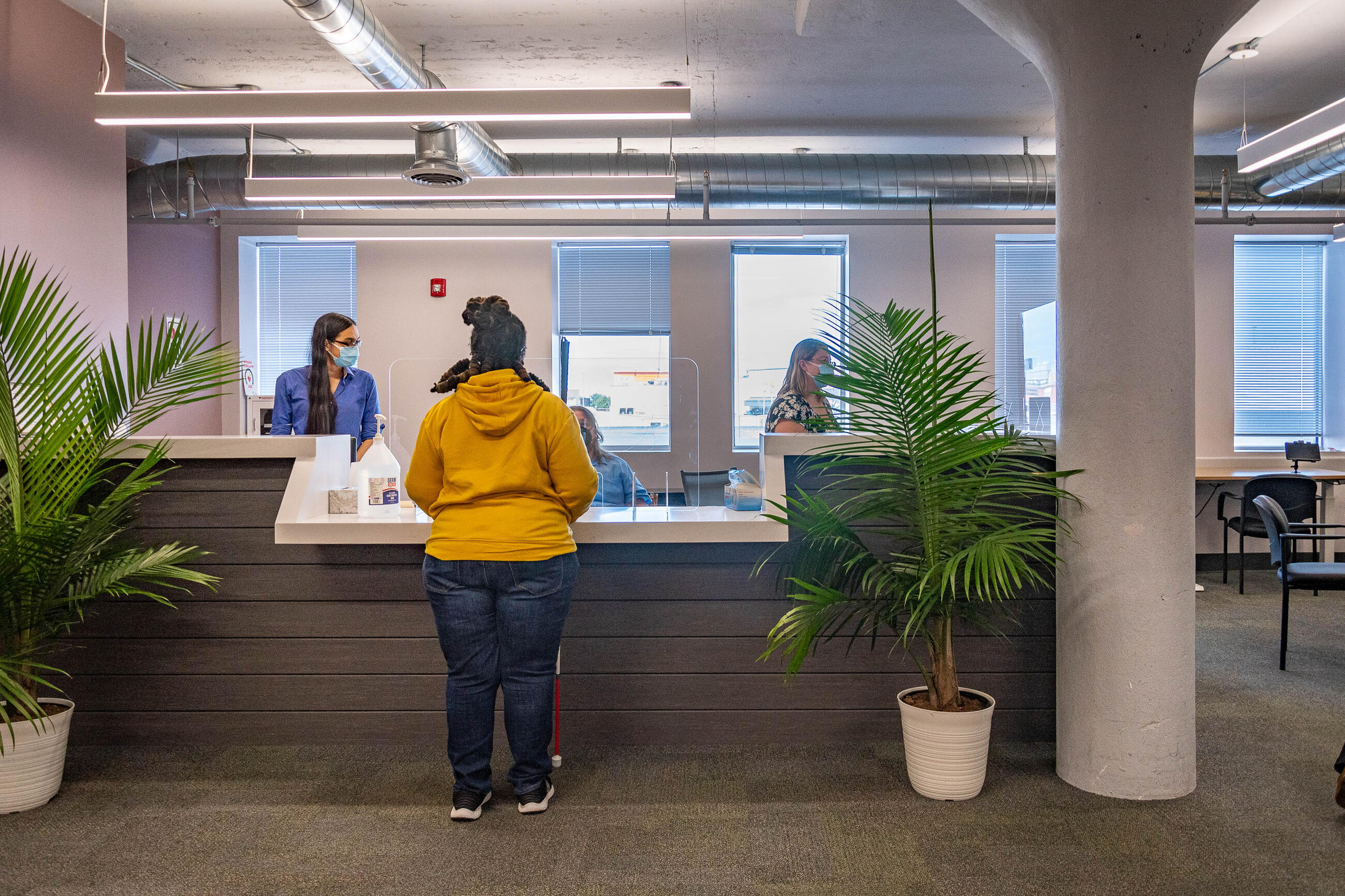 Rider seeking help at mobility center front desk with two masked employees behind desk 