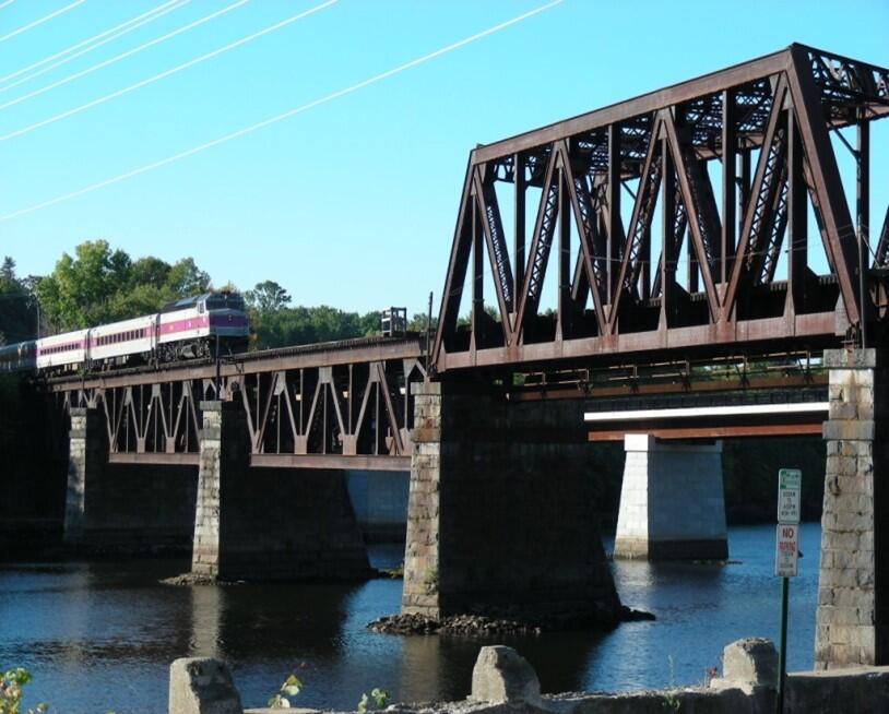 View of the Merrimack Bridge with a commuter rail train running over it 