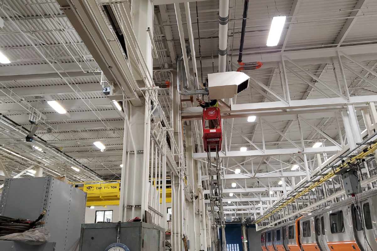 a person working in a lift near the ceiling of a very bright maintenance facility
