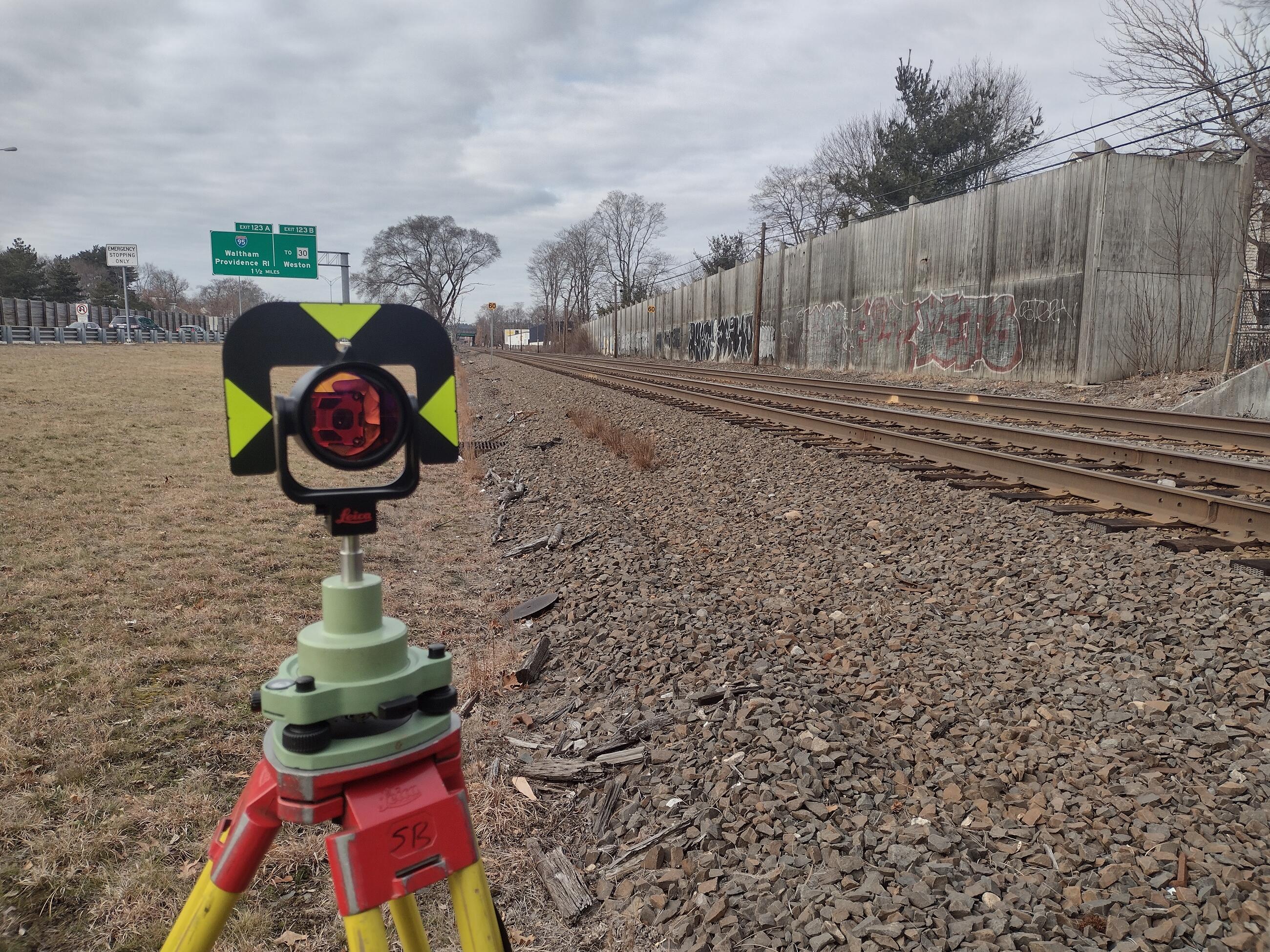 Land surveying equipment next to train tracks by the highway in Newton