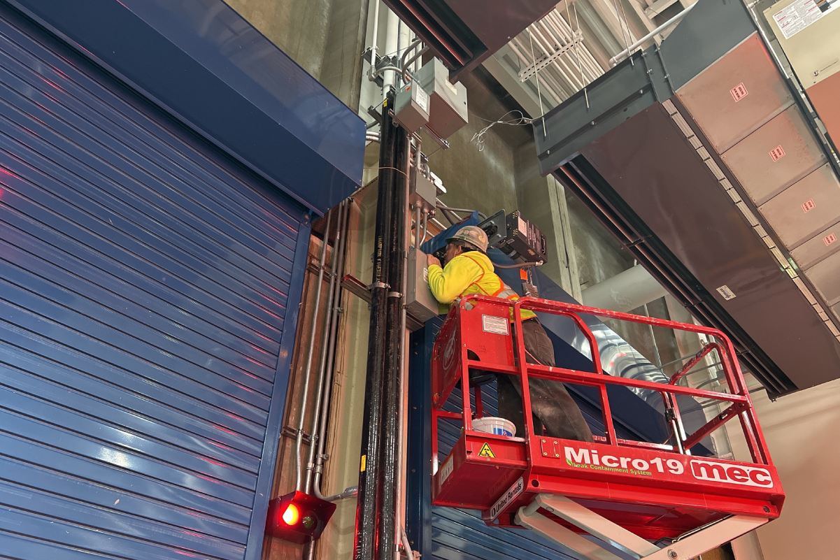 crew member in a lift painting something on the wall