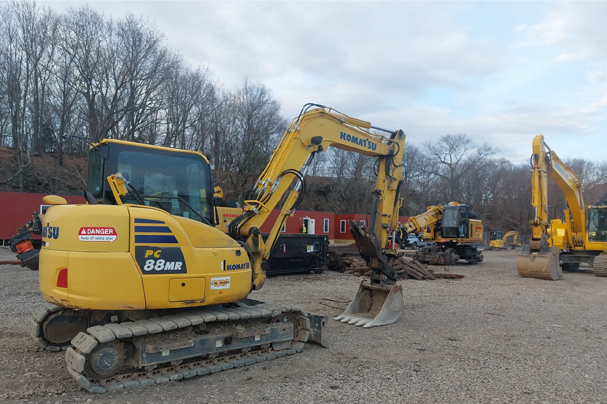 two yellow backhoes parked on gravel 